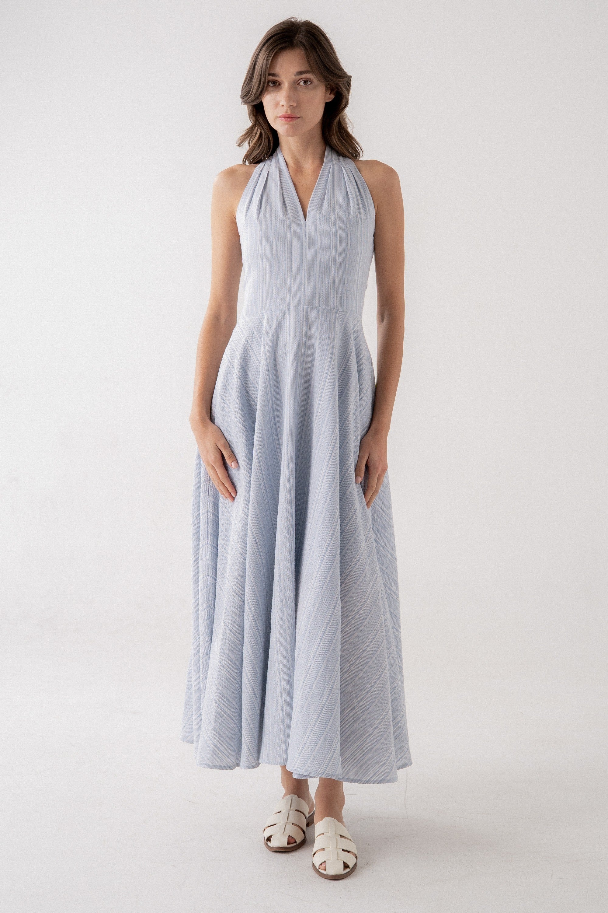 Woman wearing a light blue halter neck dress on a white background