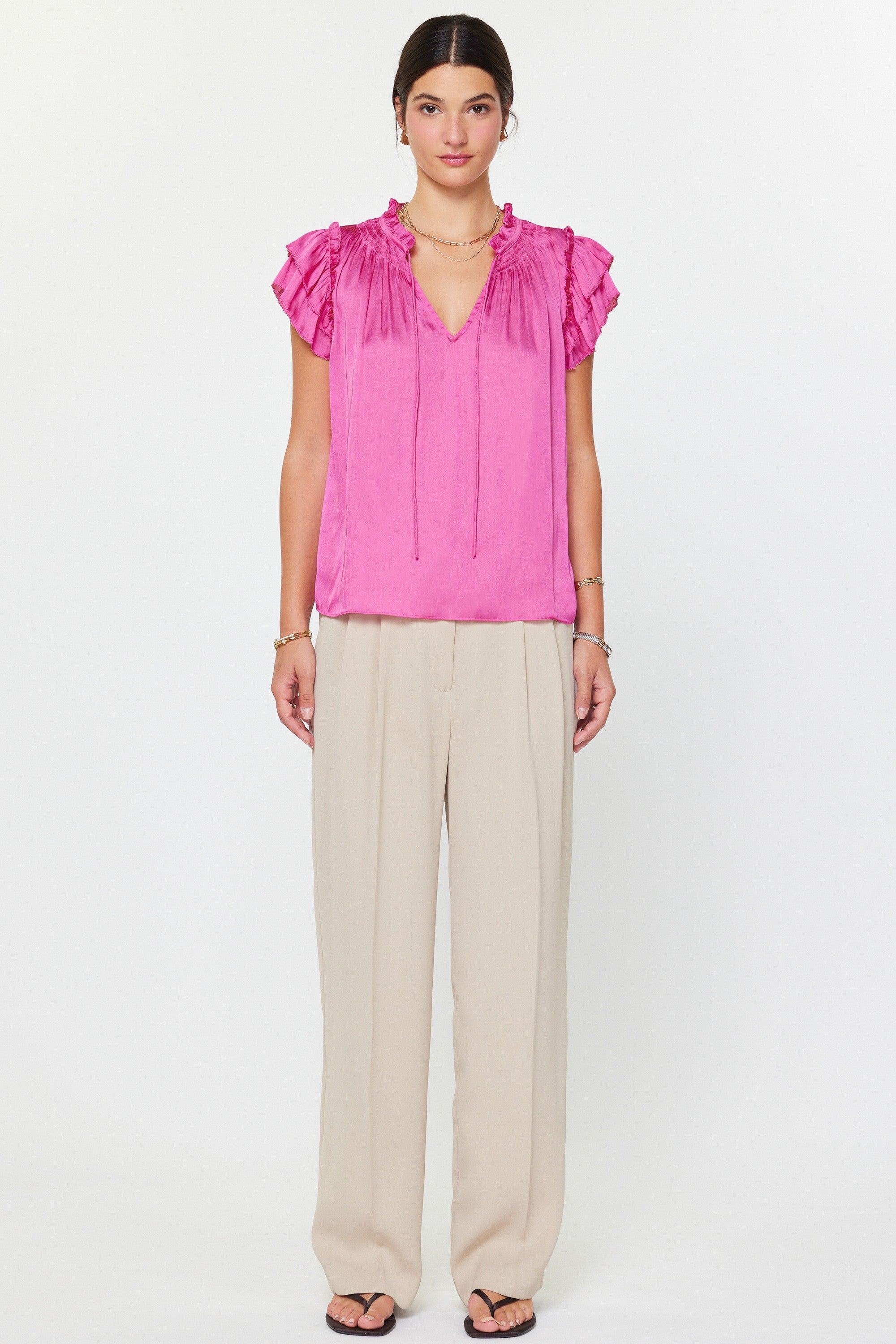 Woman wearing a pink blouse and beige pants on a white background