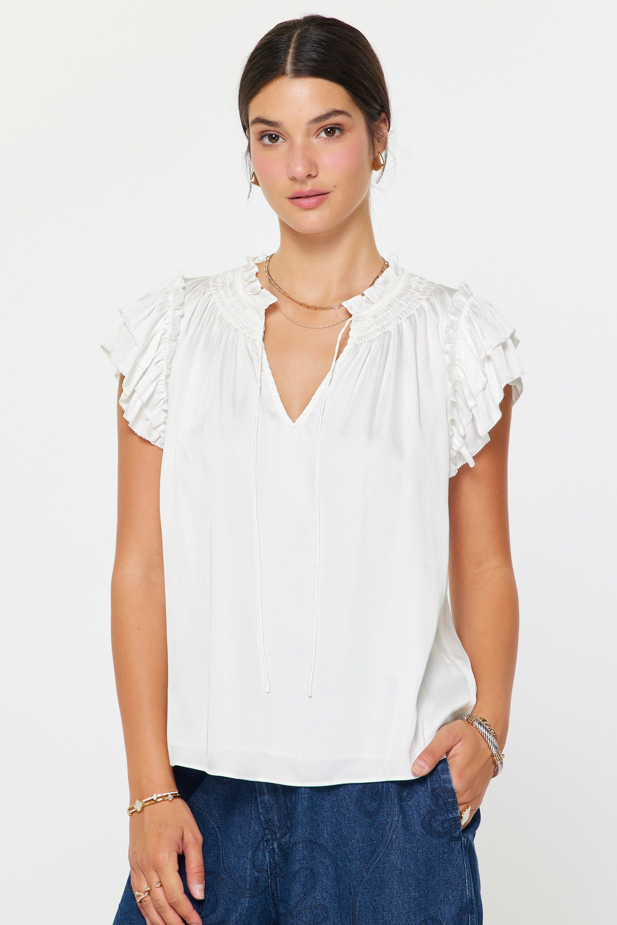 Woman wearing a white blouse with ruffled sleeves on a plain background