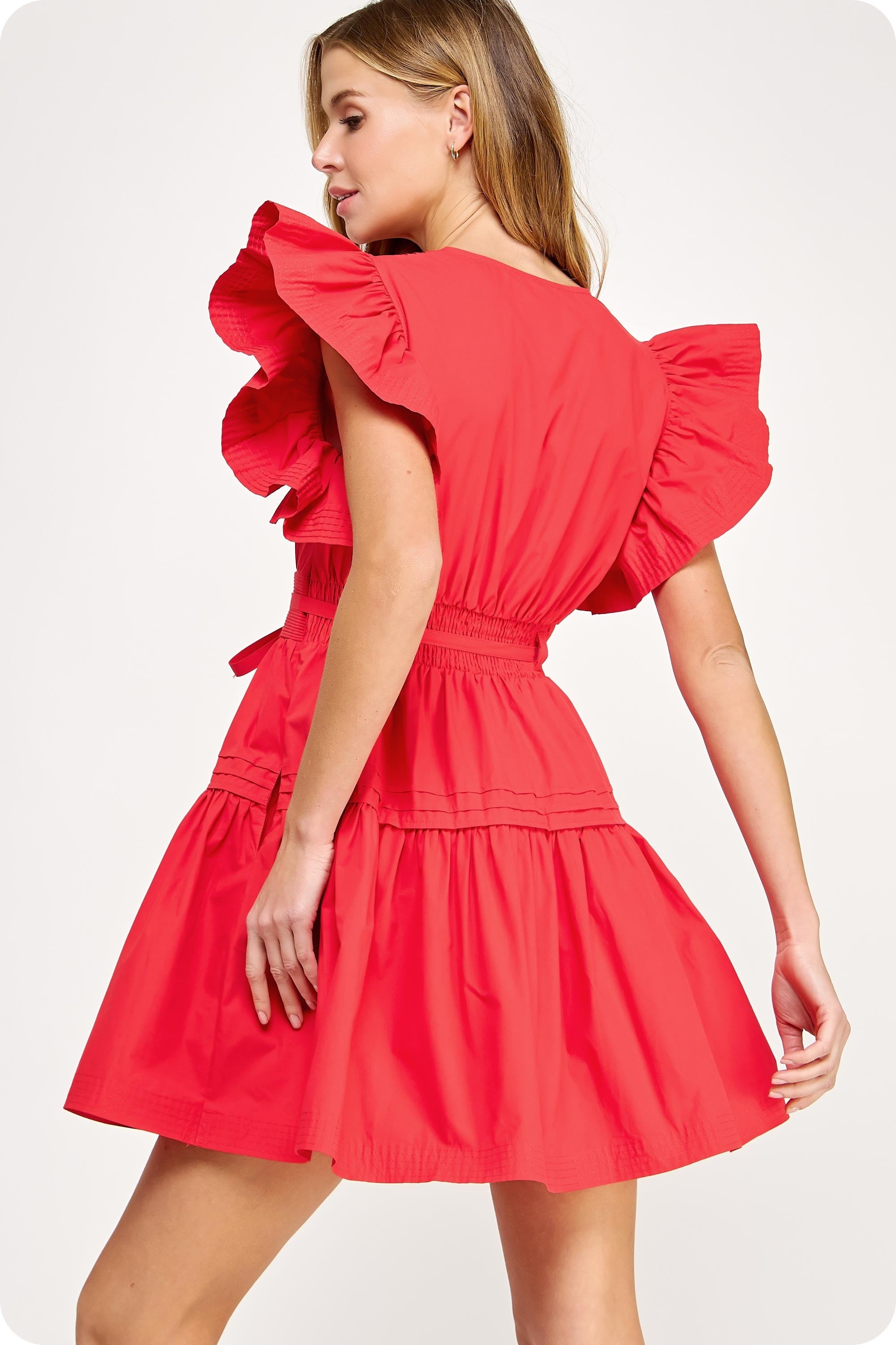 Woman wearing a red dress with ruffled sleeves on a white background