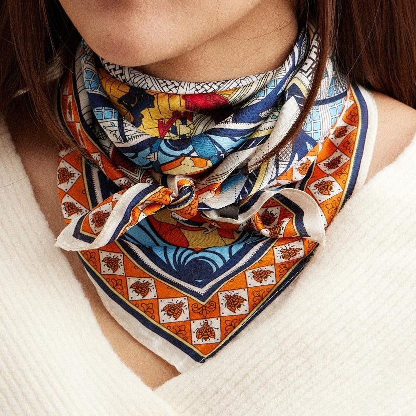 Woman wearing a colorful patterned scarf on a neutral background