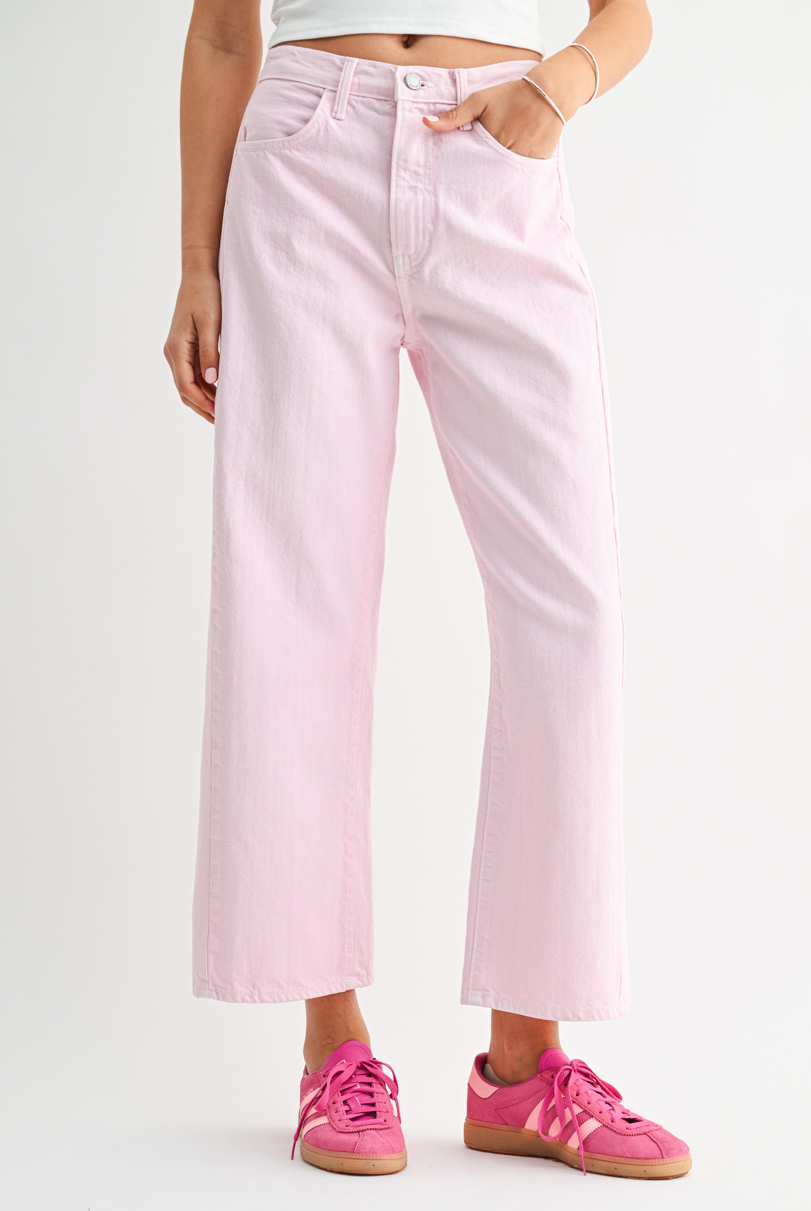 Person wearing light pink jeans and pink sneakers on a white background