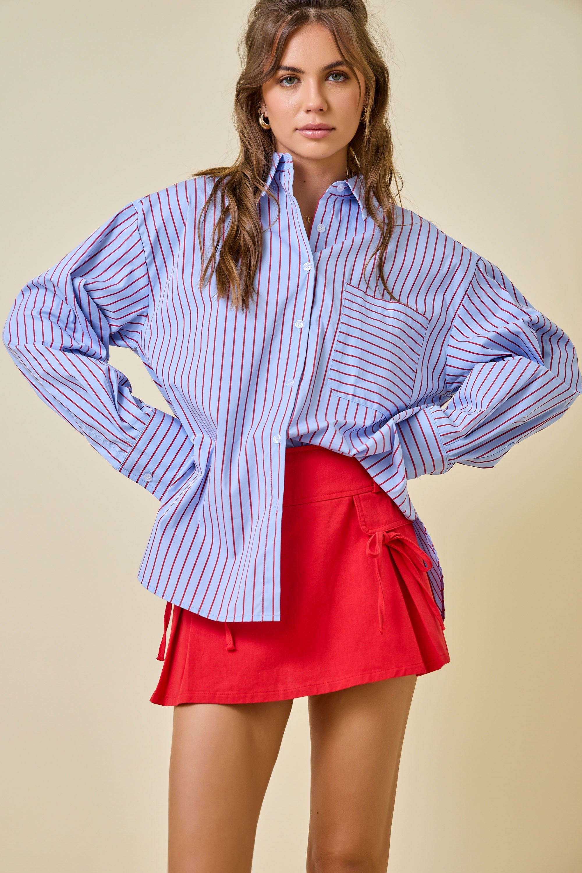 Woman wearing a blue and white striped shirt with a red skirt on a beige background