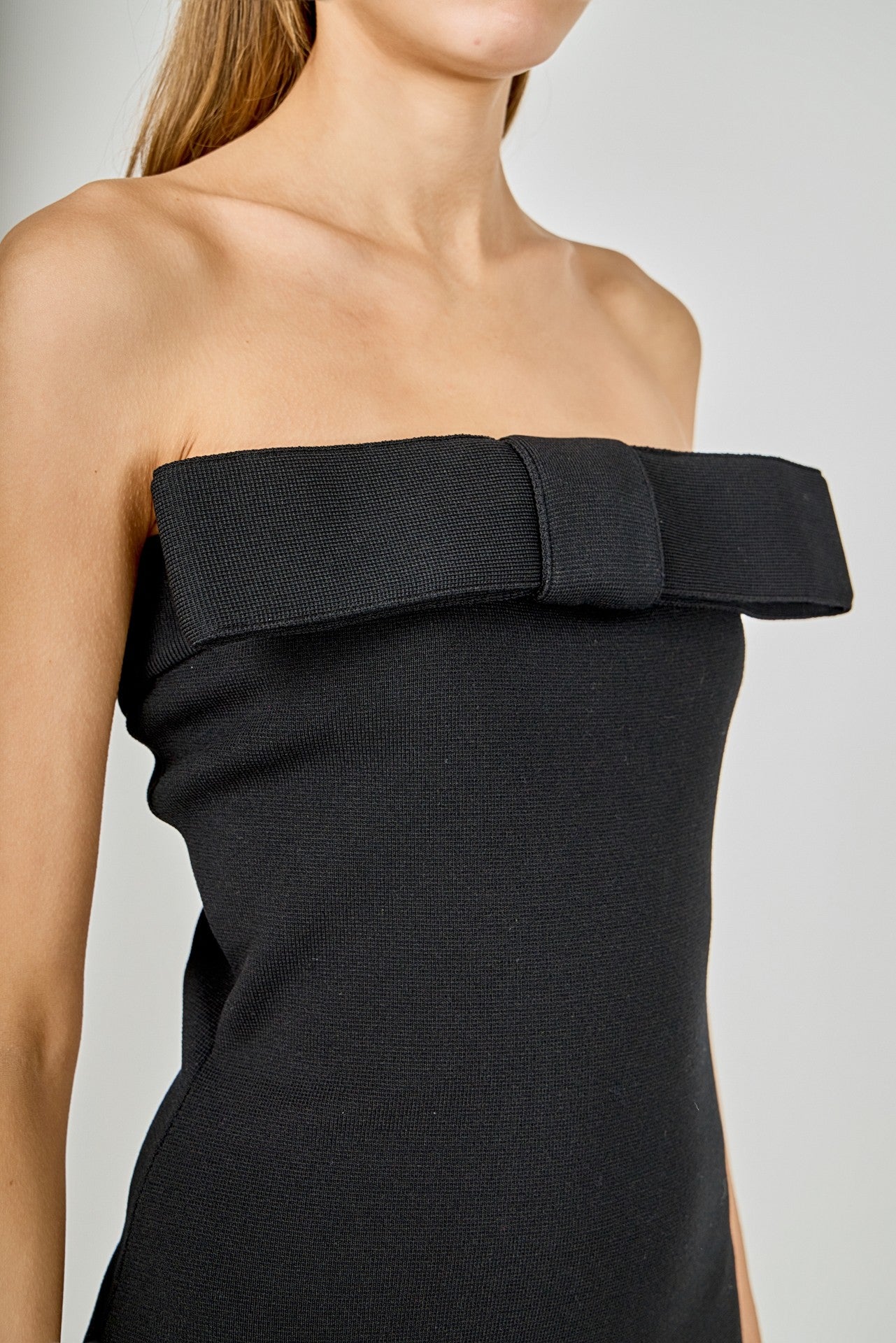 Black strapless dress with a bow detail on a neutral background