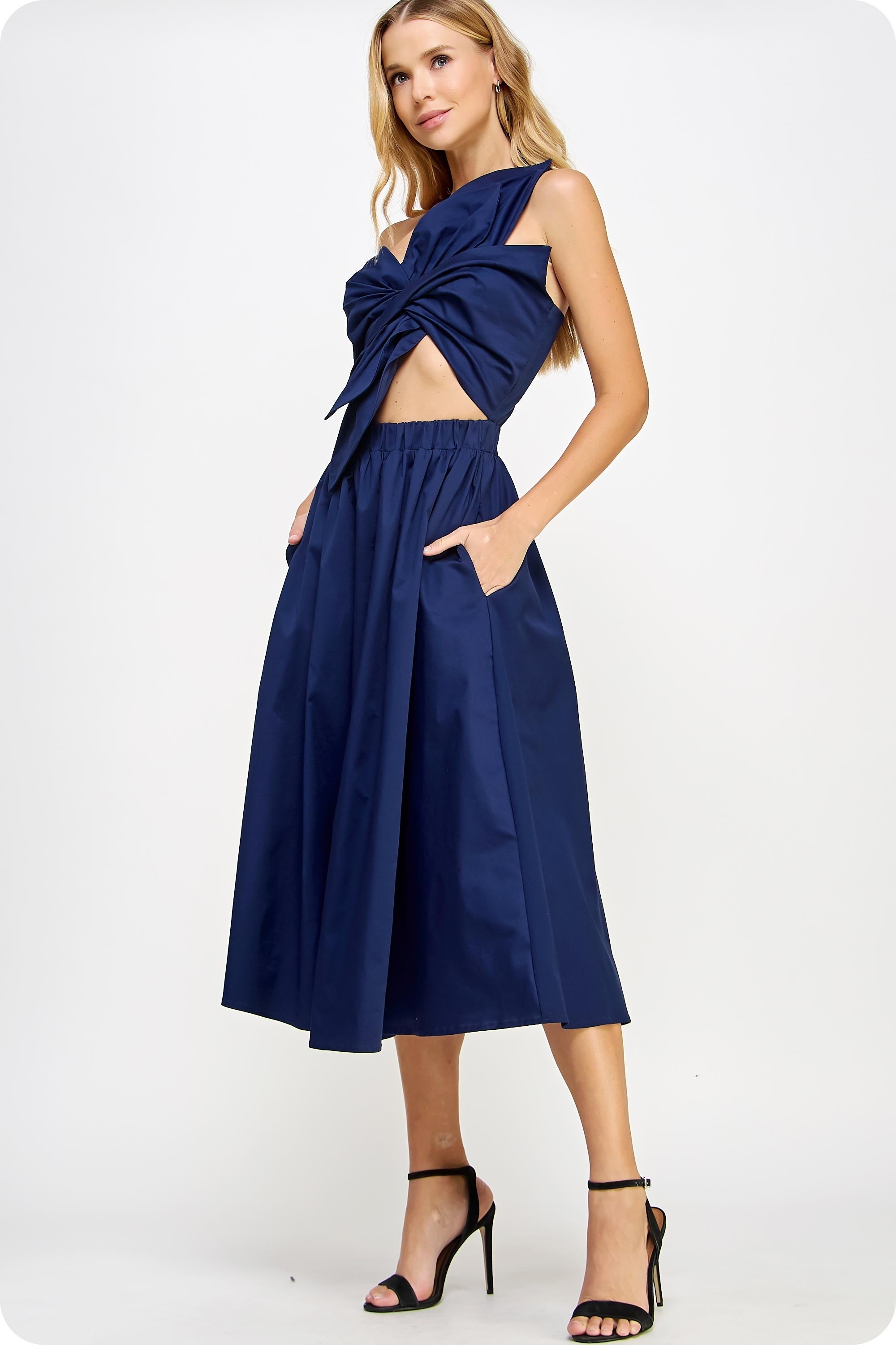 Woman wearing a navy blue dress with a cut-out design on a white background