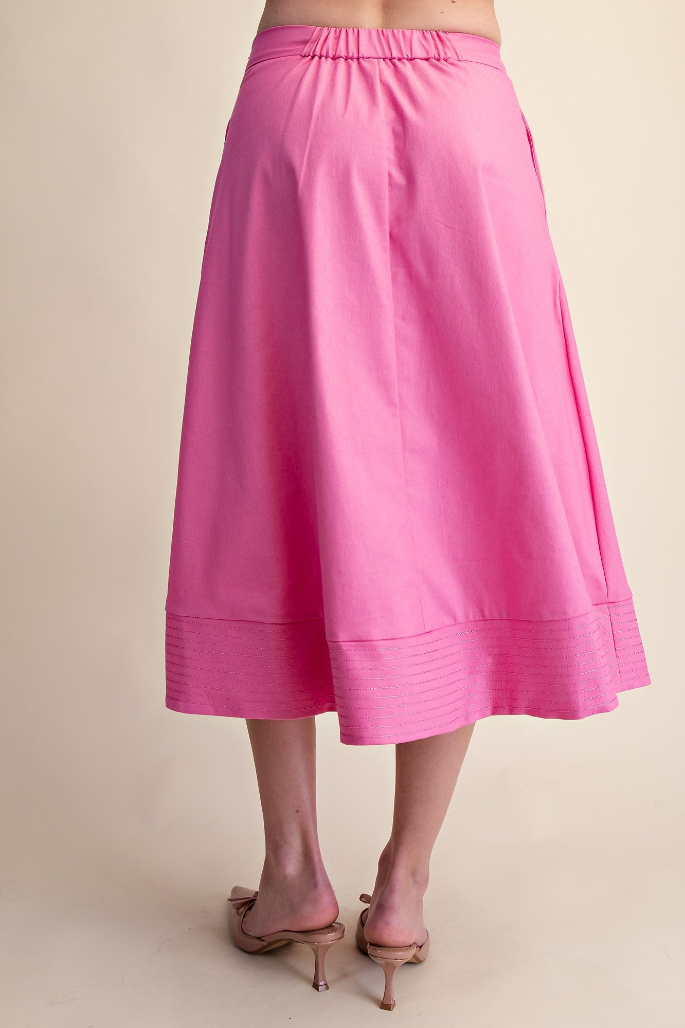 Pink skirt worn by a person on a beige background