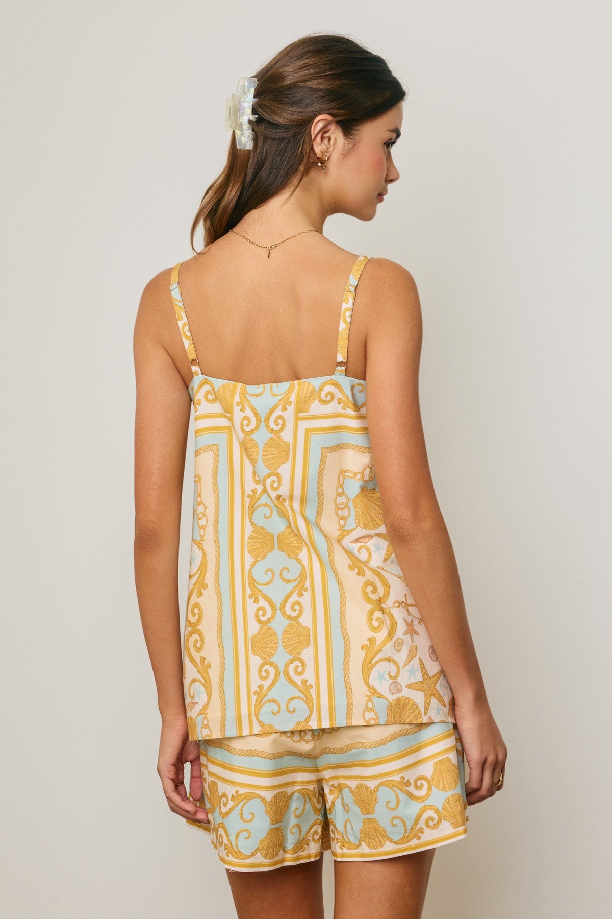 Woman wearing a yellow and blue patterned top and shorts set on a plain background
