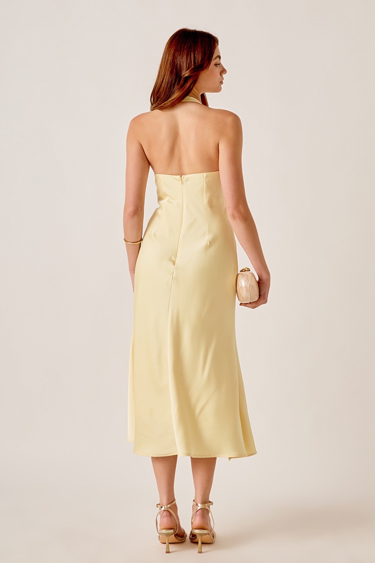 Woman wearing a strapless yellow dress on a plain background