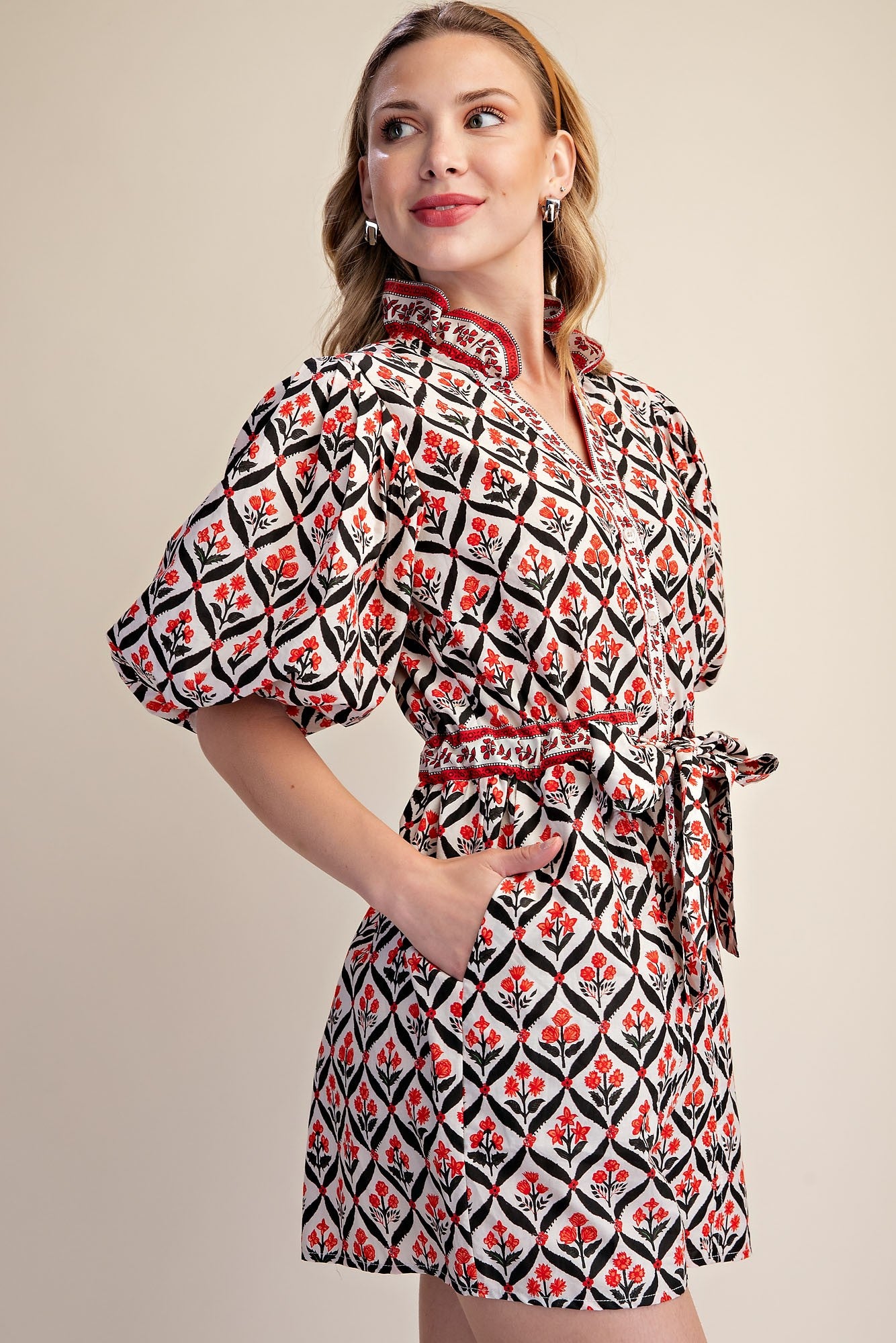 Woman wearing a patterned dress with puff sleeves on a beige background