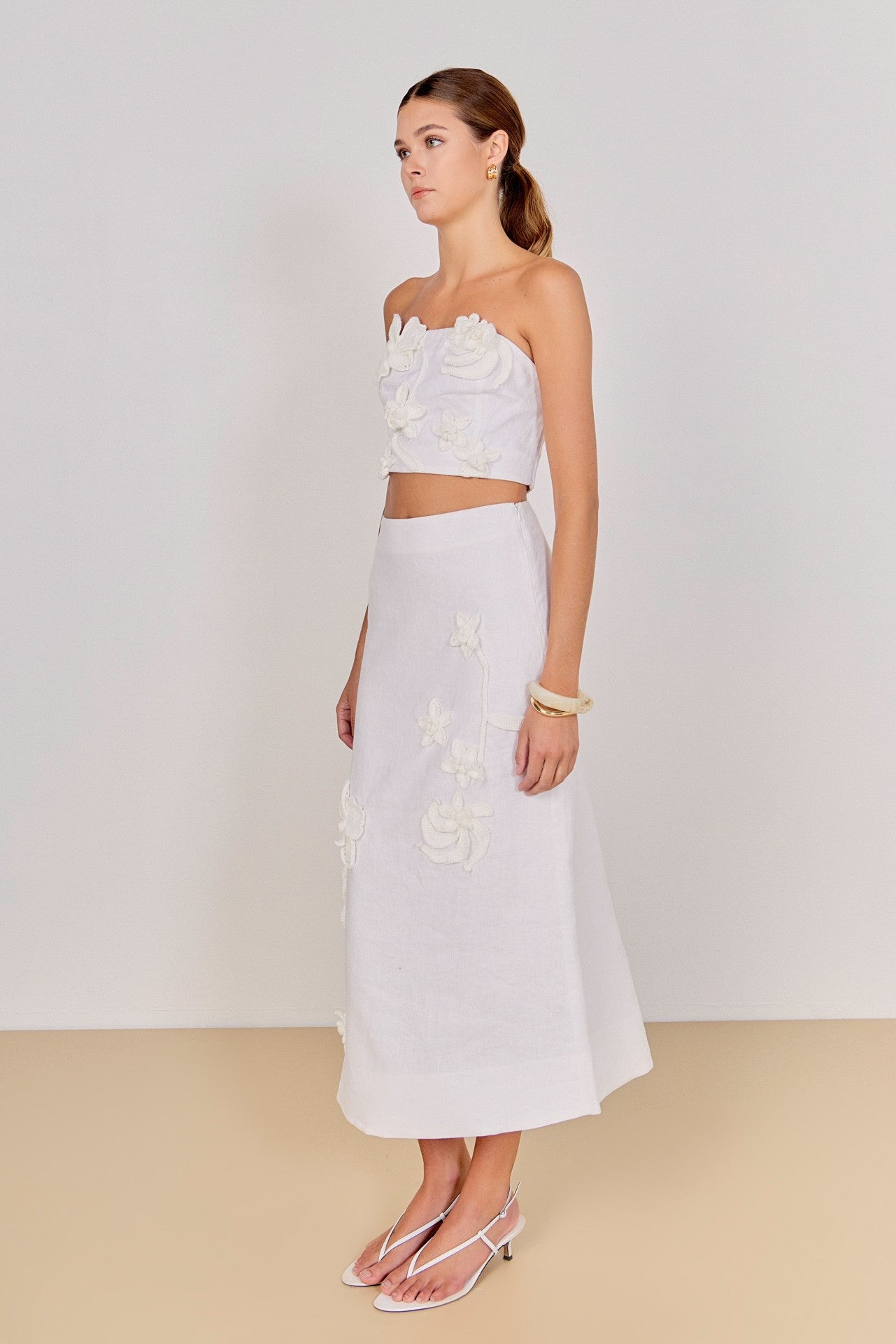 Woman wearing a white floral top and skirt set on a plain background