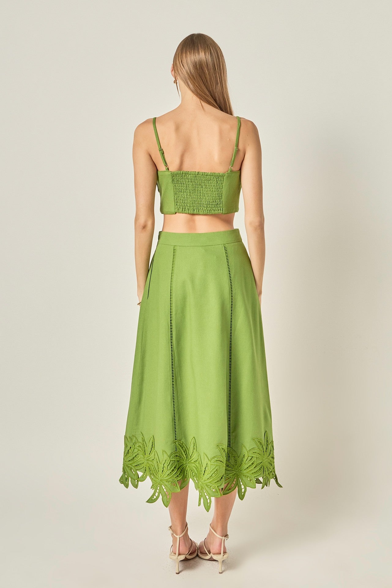 Woman wearing a green set with lace details on a plain background