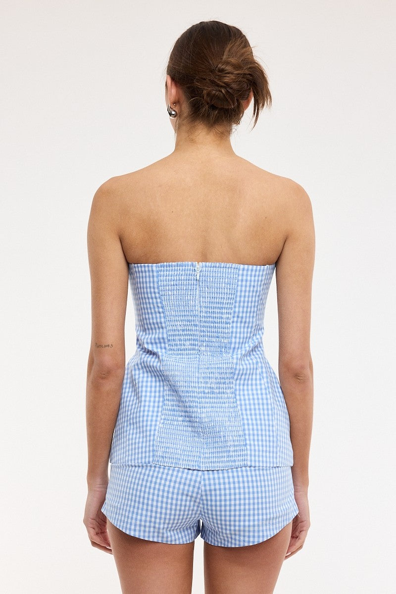 Woman wearing a blue checkered strapless top and shorts set on a white background