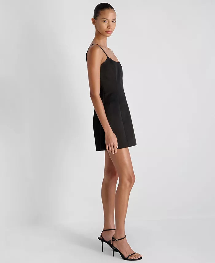 Woman wearing a black slip dress on a plain background