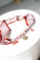 Red and white patterned scarf with decorative charms on a white surface