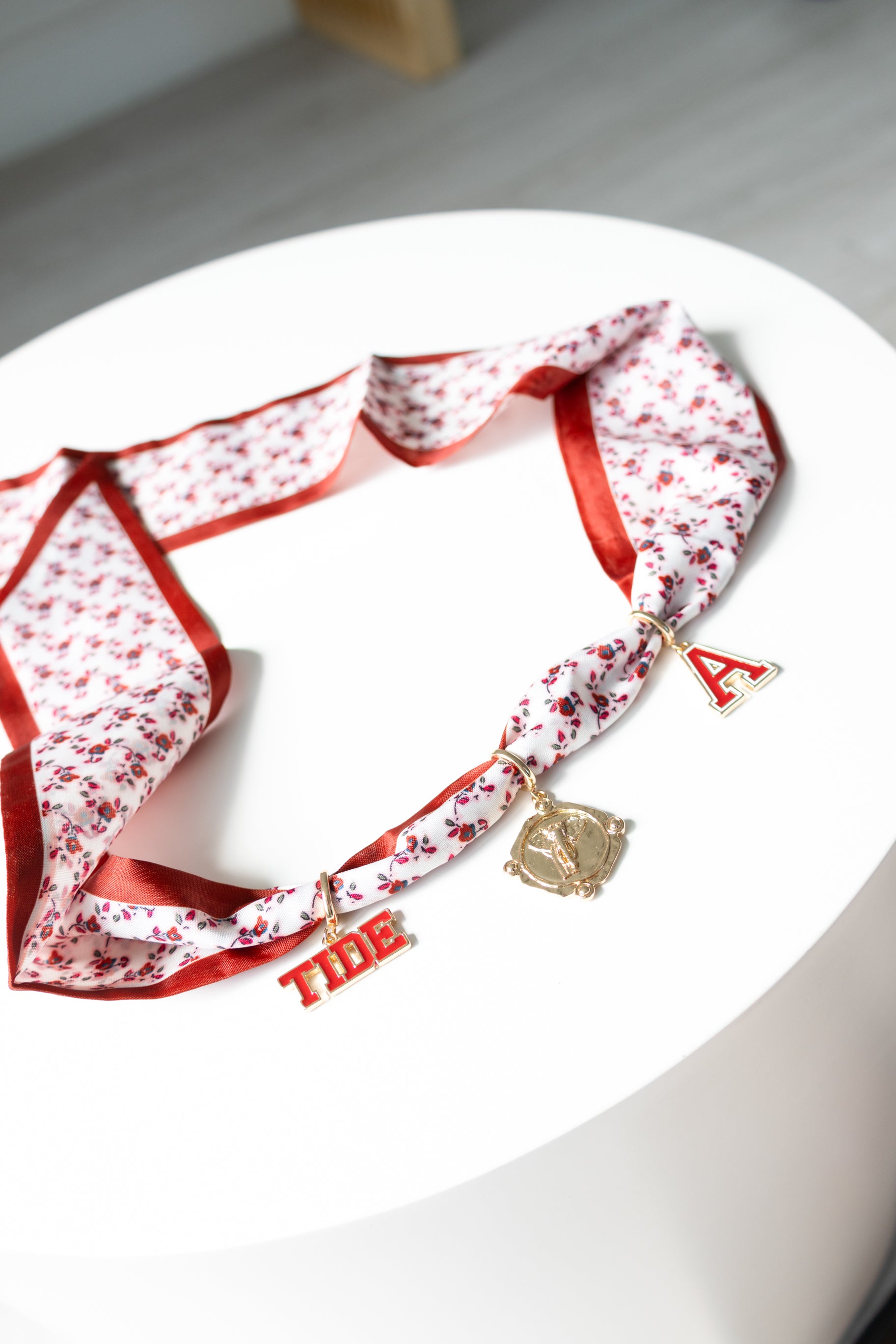 Red and white patterned scarf with decorative charms on a white surface