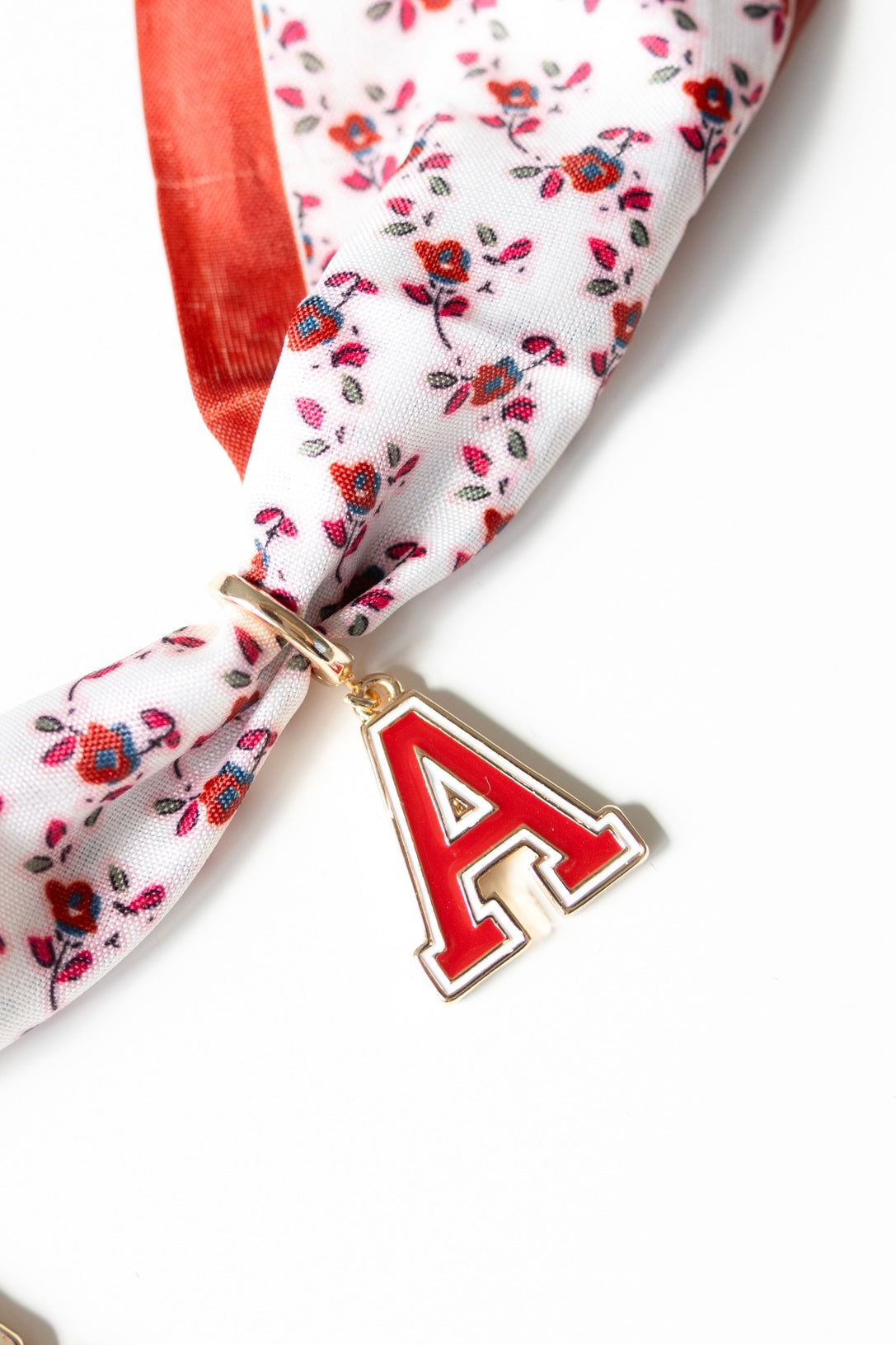 Floral scarf with a red 'A' charm on a white background
