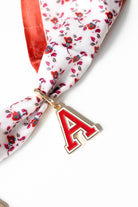 Floral scarf with a red 'A' charm on a white background