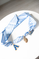 Blue and white striped scarf with decorative pendant game day charms on a white surface