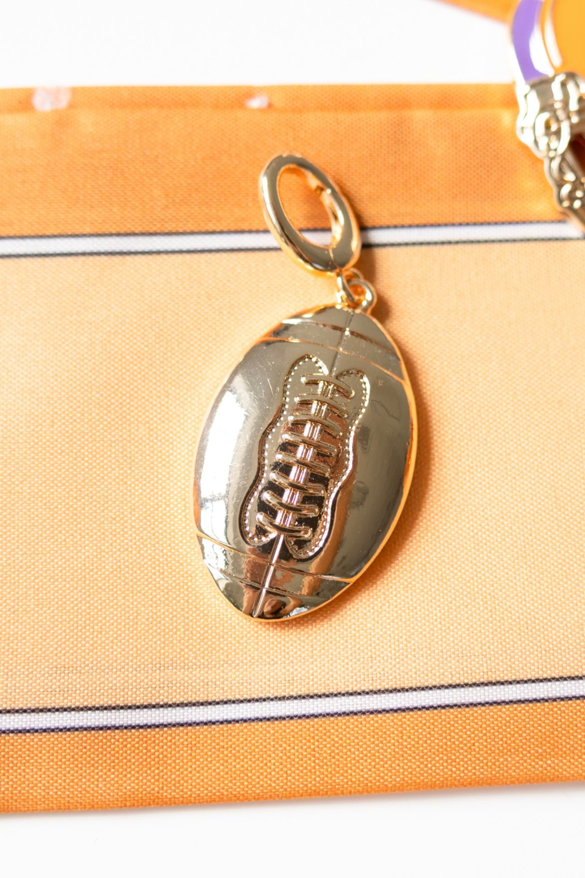 Gold football-shaped pendant on a orange fabric background