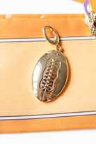 Gold football-shaped pendant on a orange fabric background