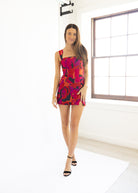 Woman wearing a colorful dress standing in a room with a window.