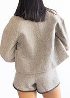Person wearing a beige jacket and shorts set on a white background