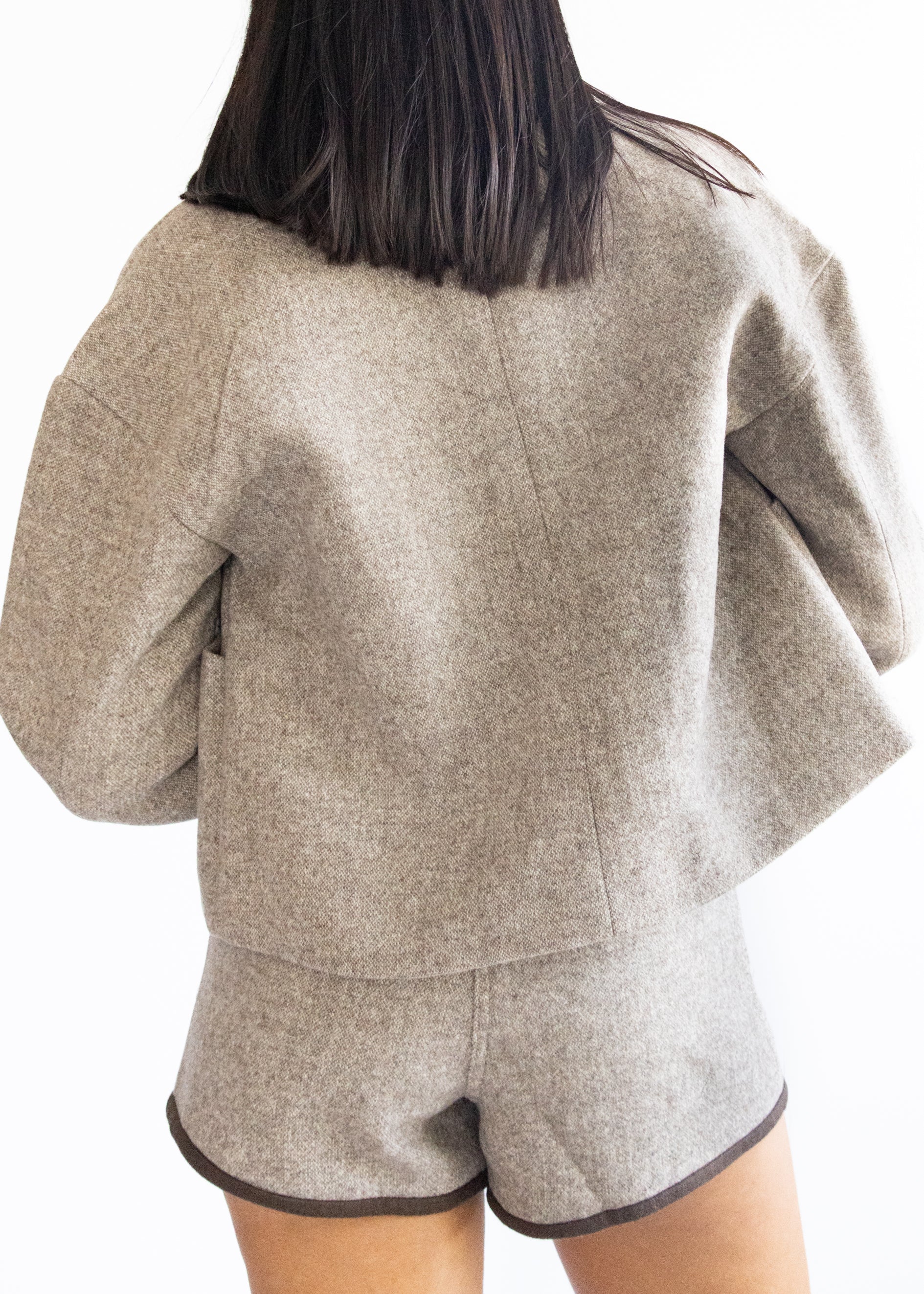 Person wearing a beige jacket and shorts set on a white background