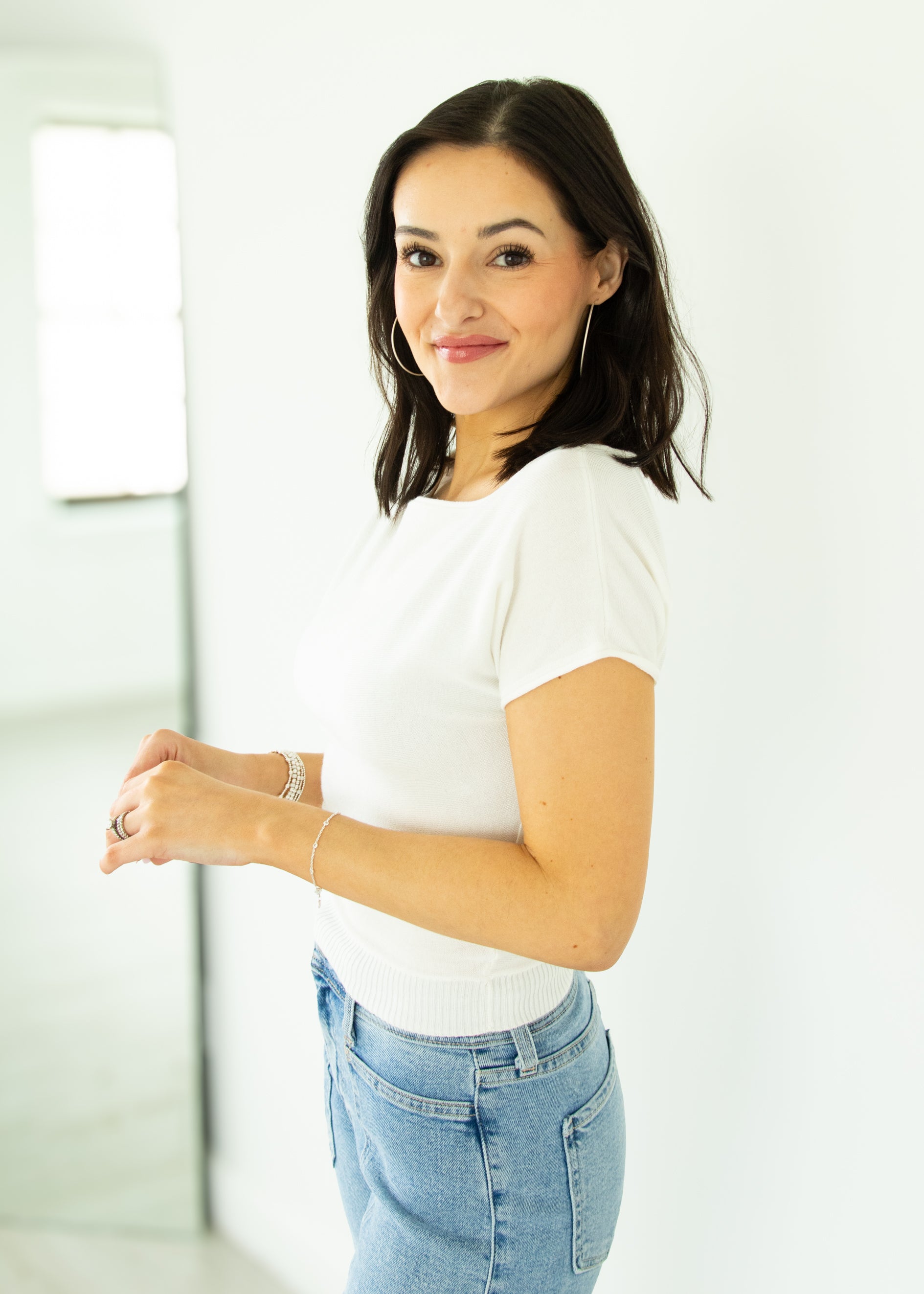 Woman wearing a white t-shirt and blue jeans against a white background