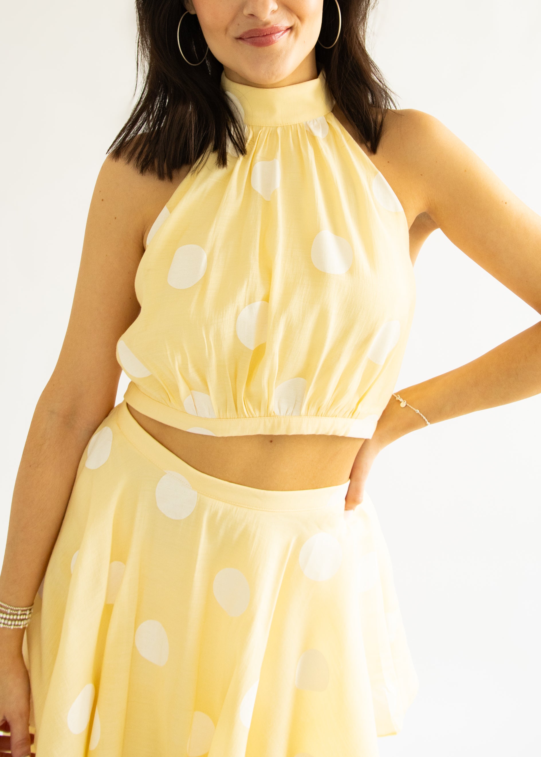 Woman wearing a yellow polka dot dress against a white background