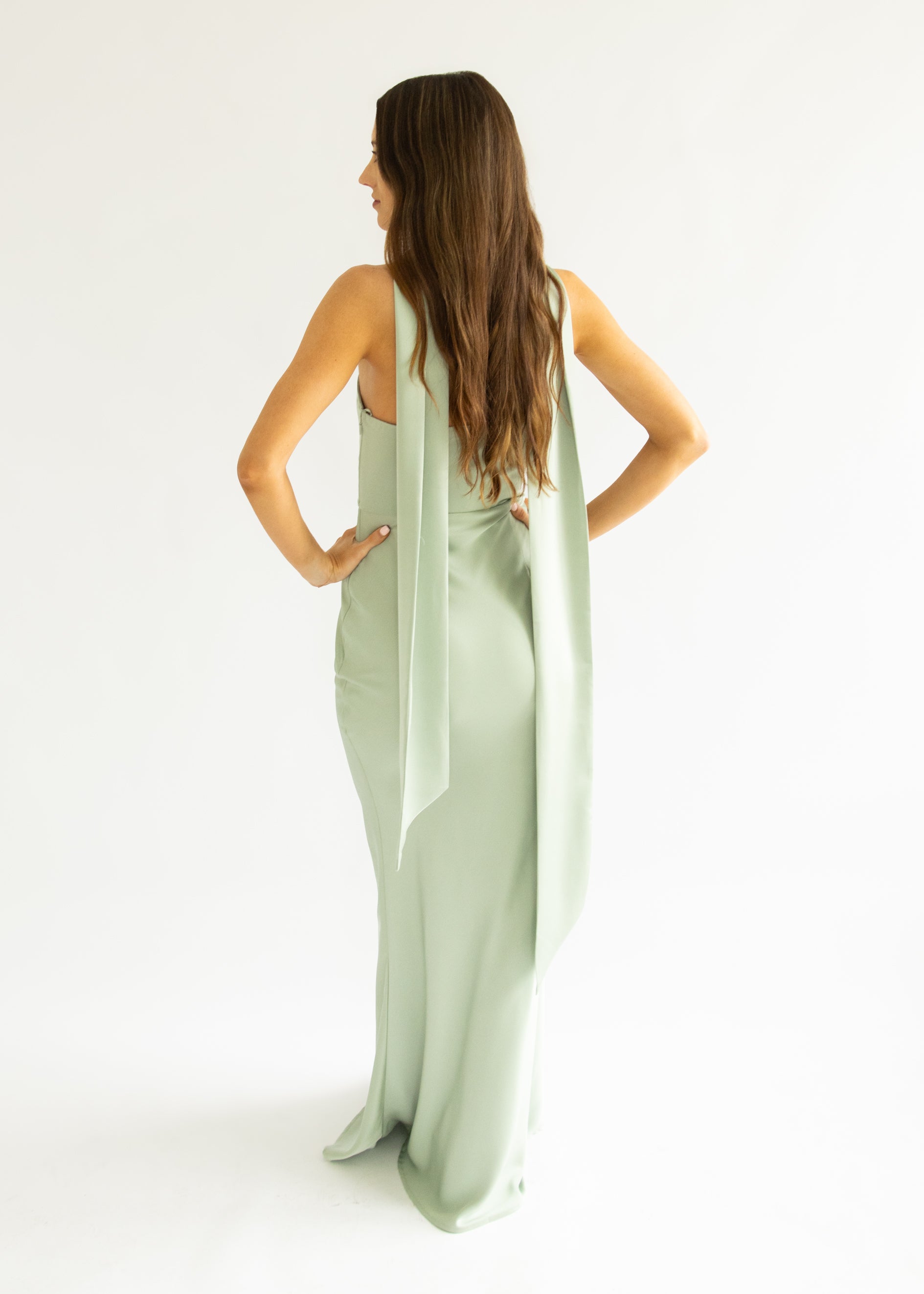 Woman wearing a light green halter neck dress on a white background