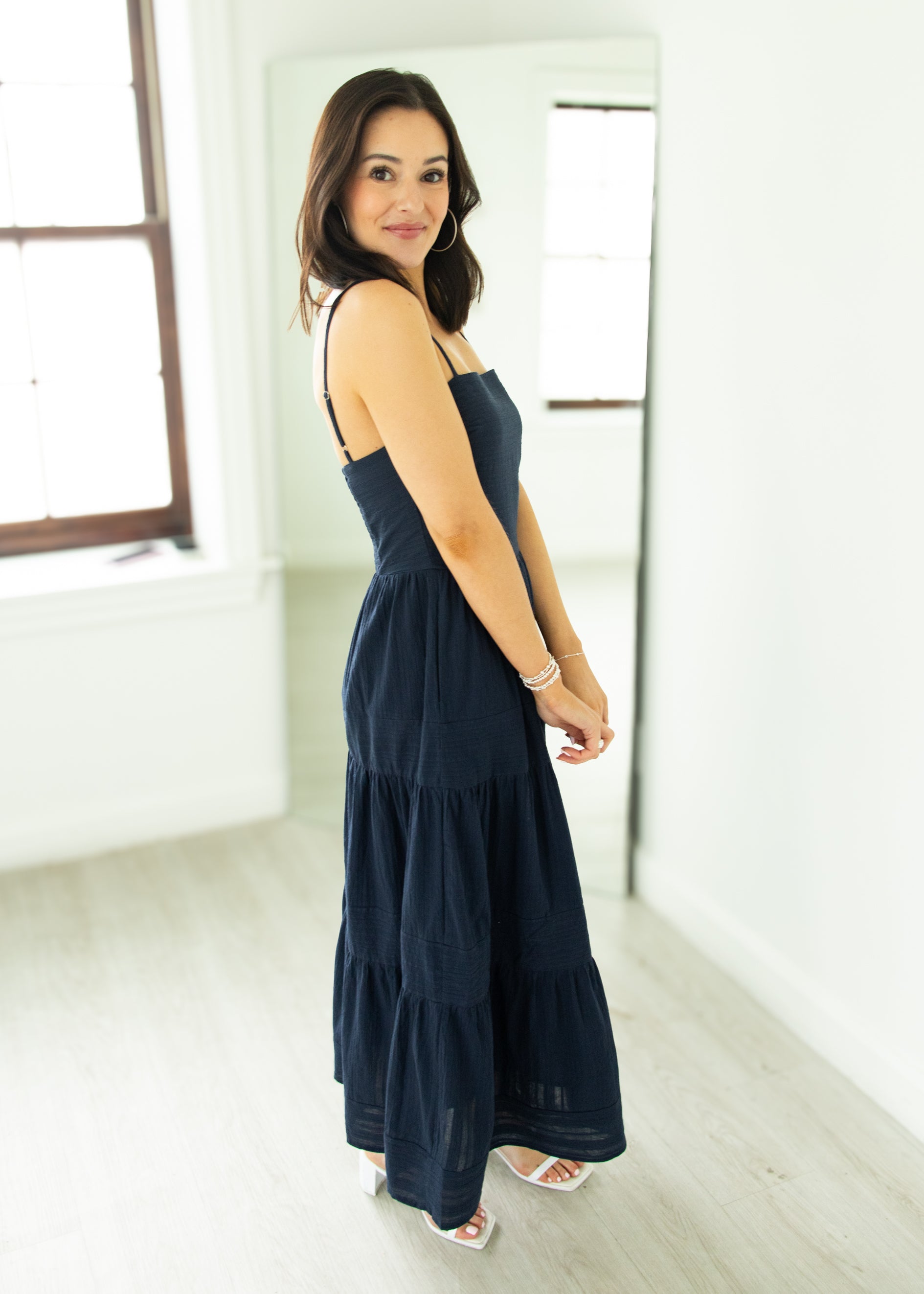 Woman wearing a navy blue dress in a minimal white room