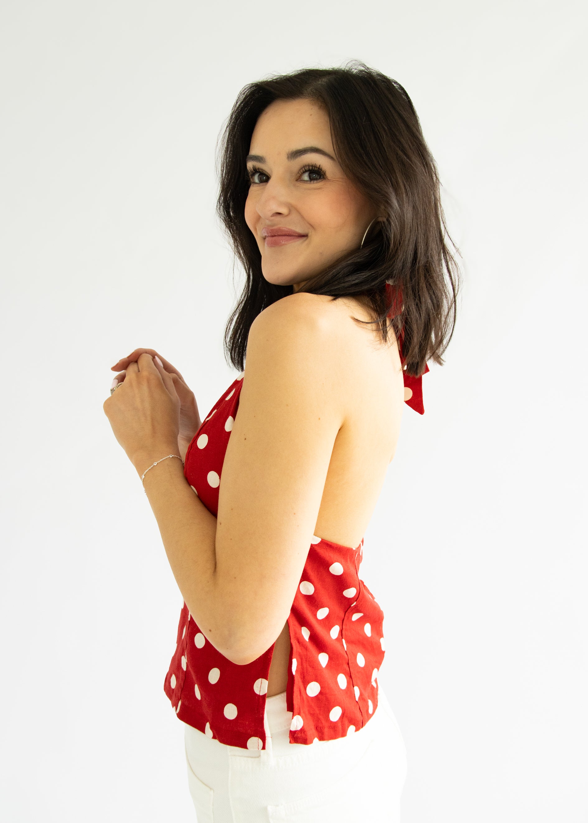 Woman wearing a red polka dot top against a white background