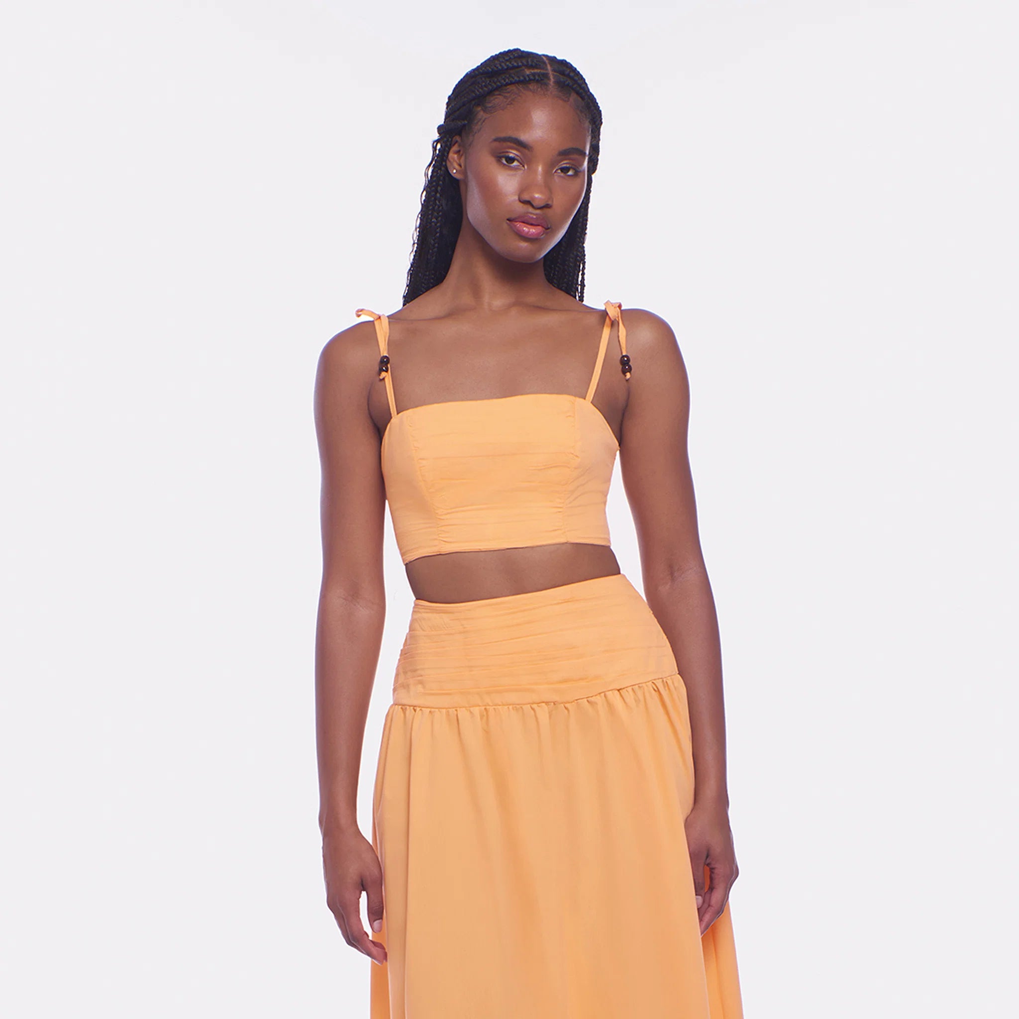 Woman wearing a mustard yellow two-piece outfit on a white background