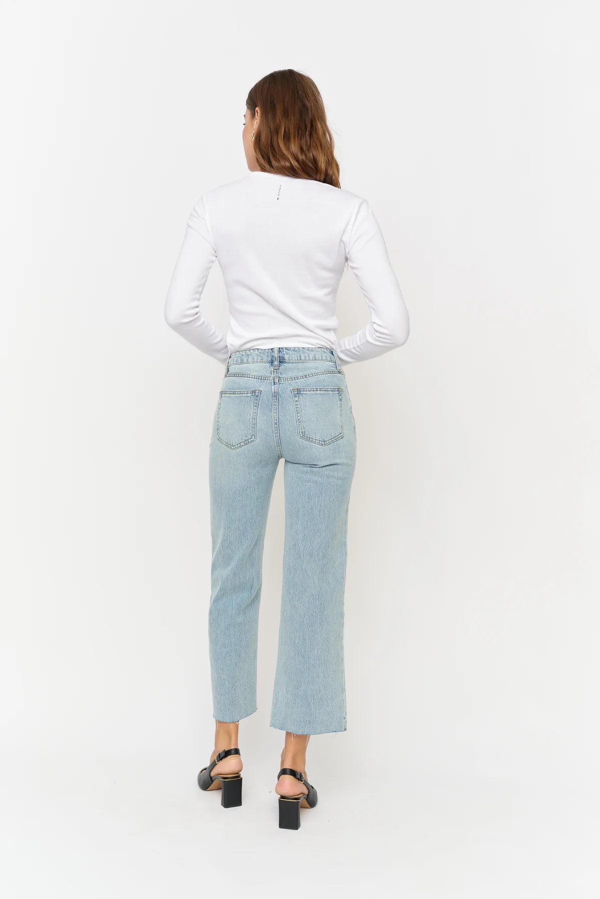 Person wearing light blue jeans and a white shirt on a white background