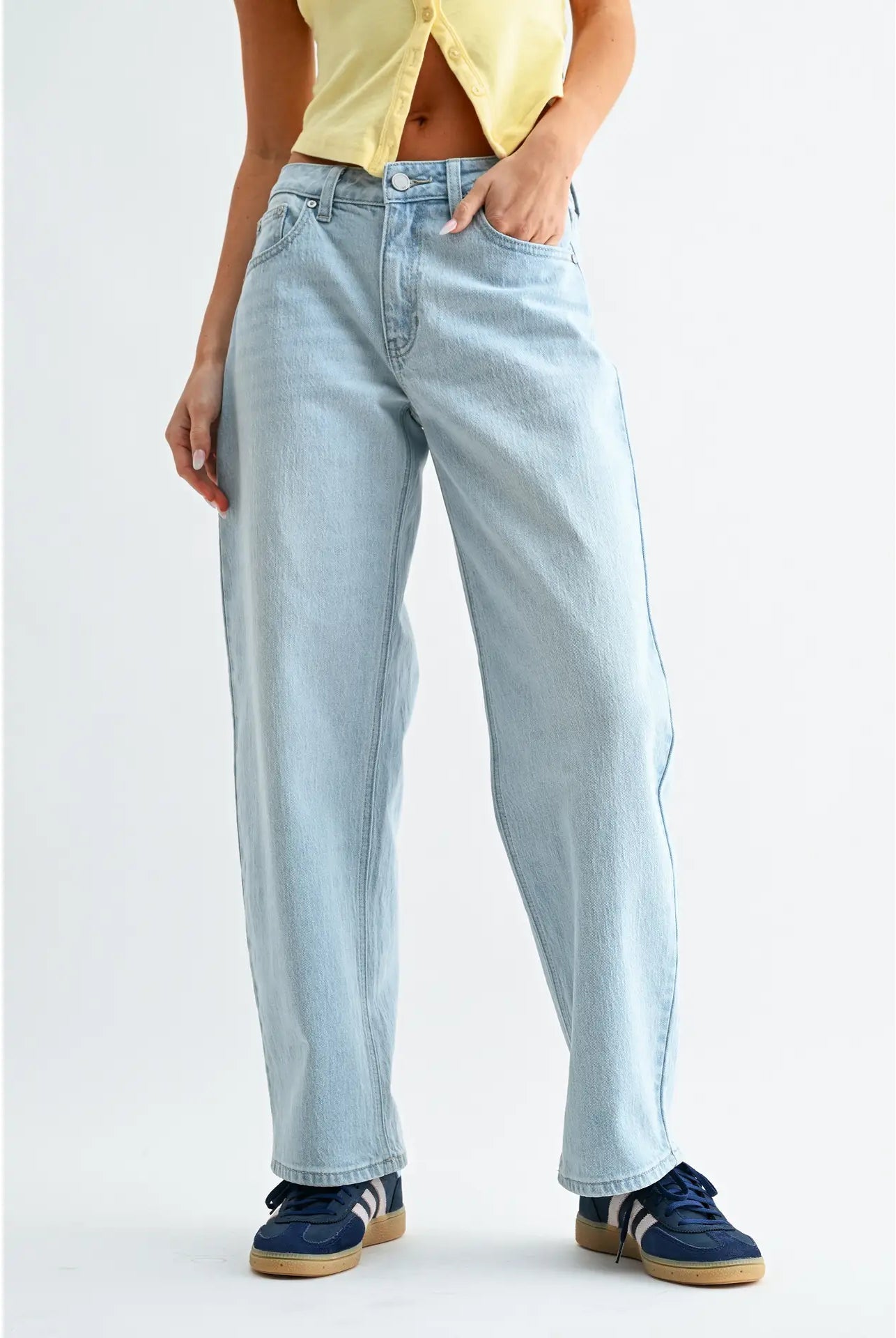 Person wearing light blue jeans and a yellow top on a white background