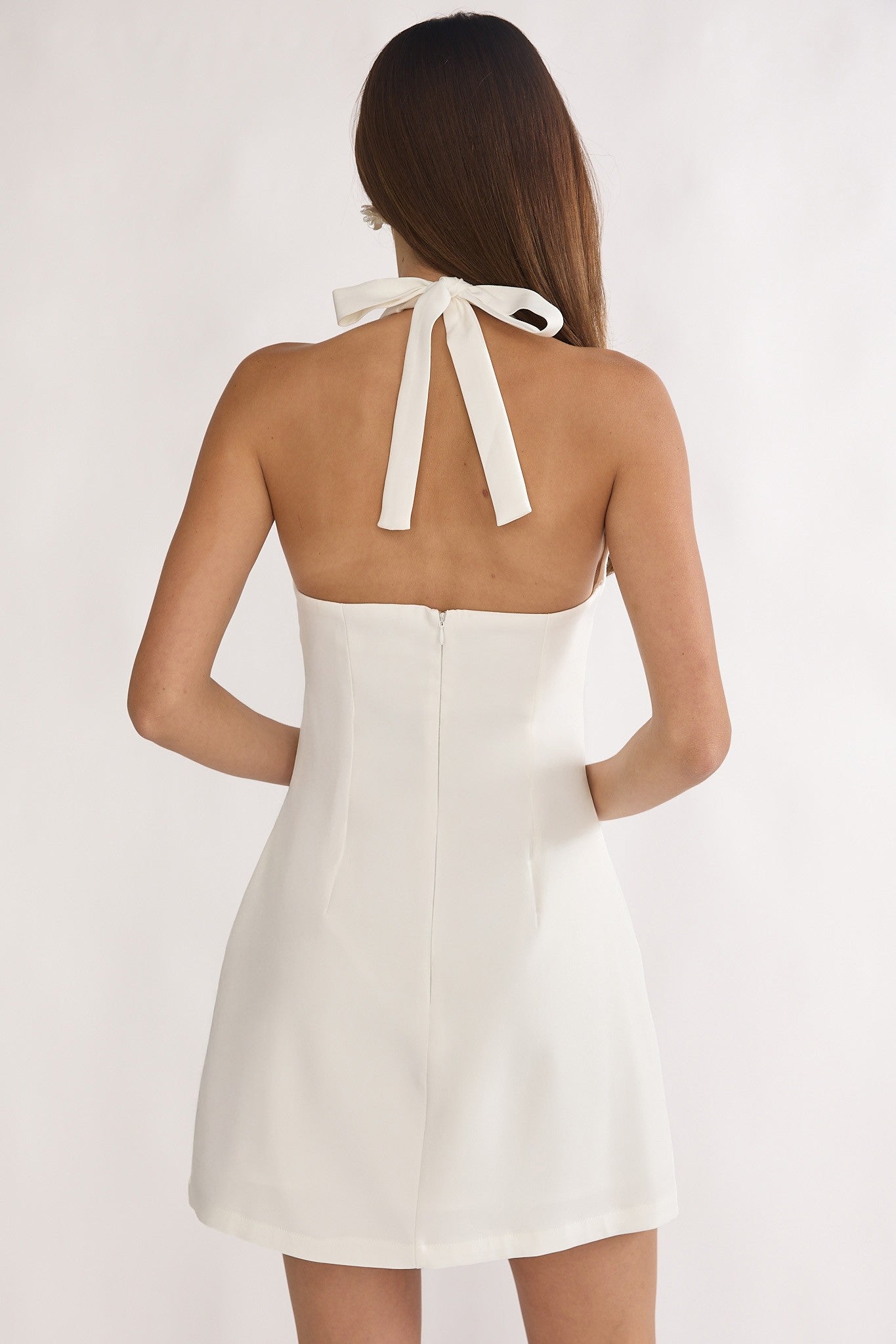 White dress with a bow detail on the back, worn by a person against a white background