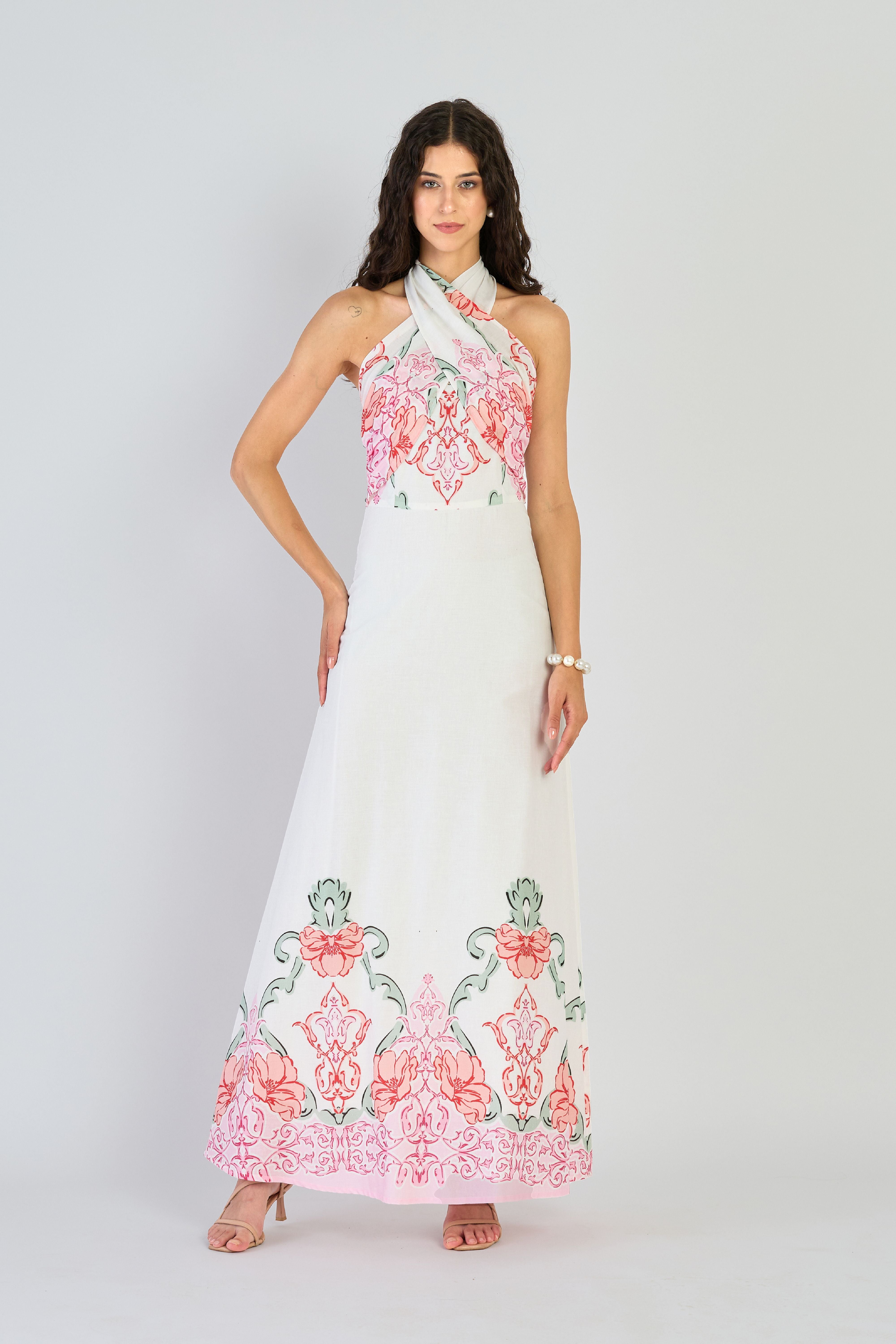 Woman wearing a white dress with floral embroidery on a plain background