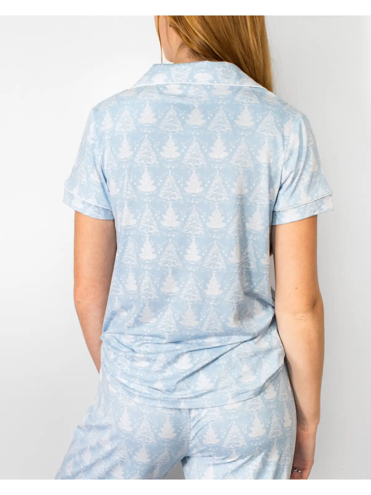 A woman shown from the back wearing a light blue short-sleeve collared top and matching pants with a white tree pattern, against a plain light background.