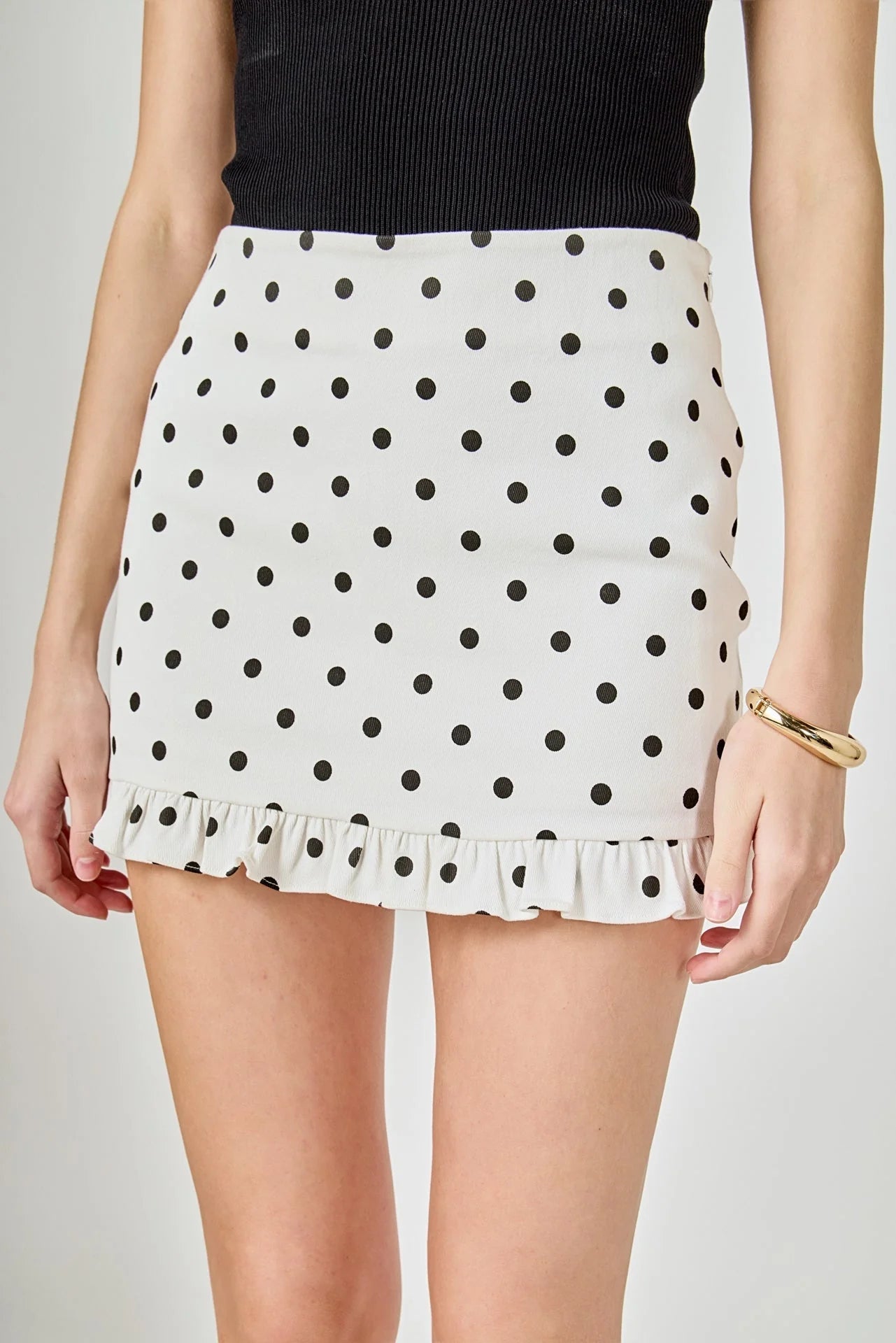White polka dot skirt with black dots on a plain background