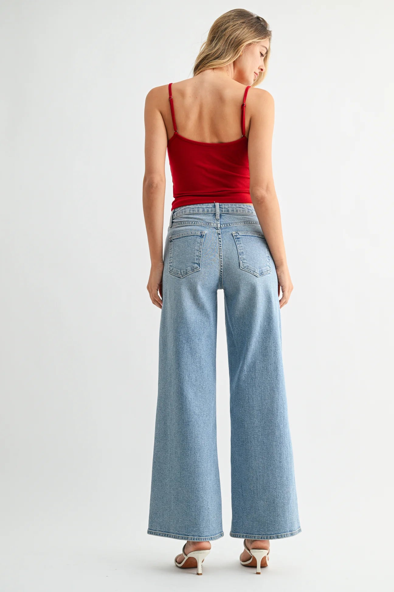 Woman wearing a red top and light blue jeans on a white background
