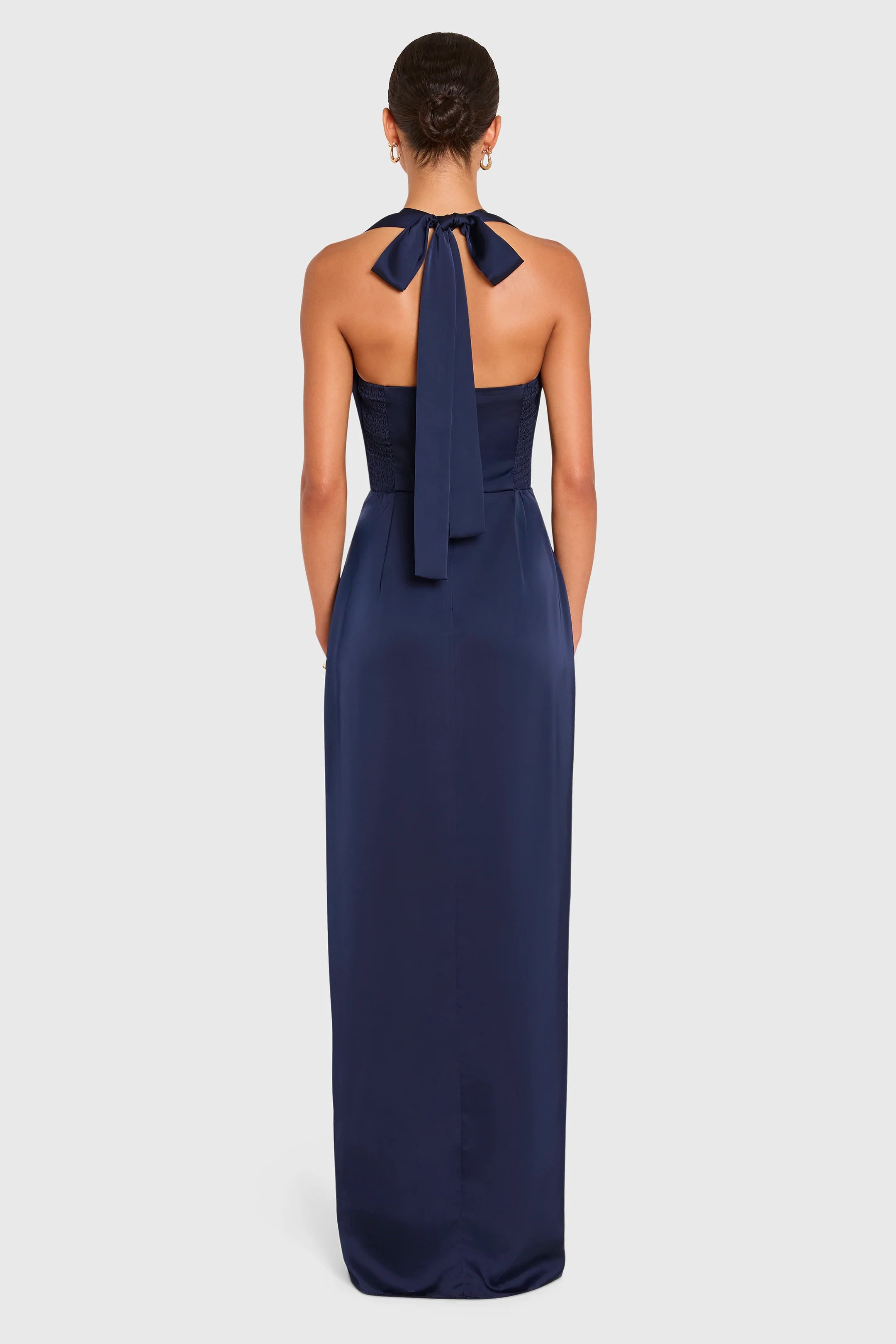 Navy blue halter neck gown with a bow detail on a white background