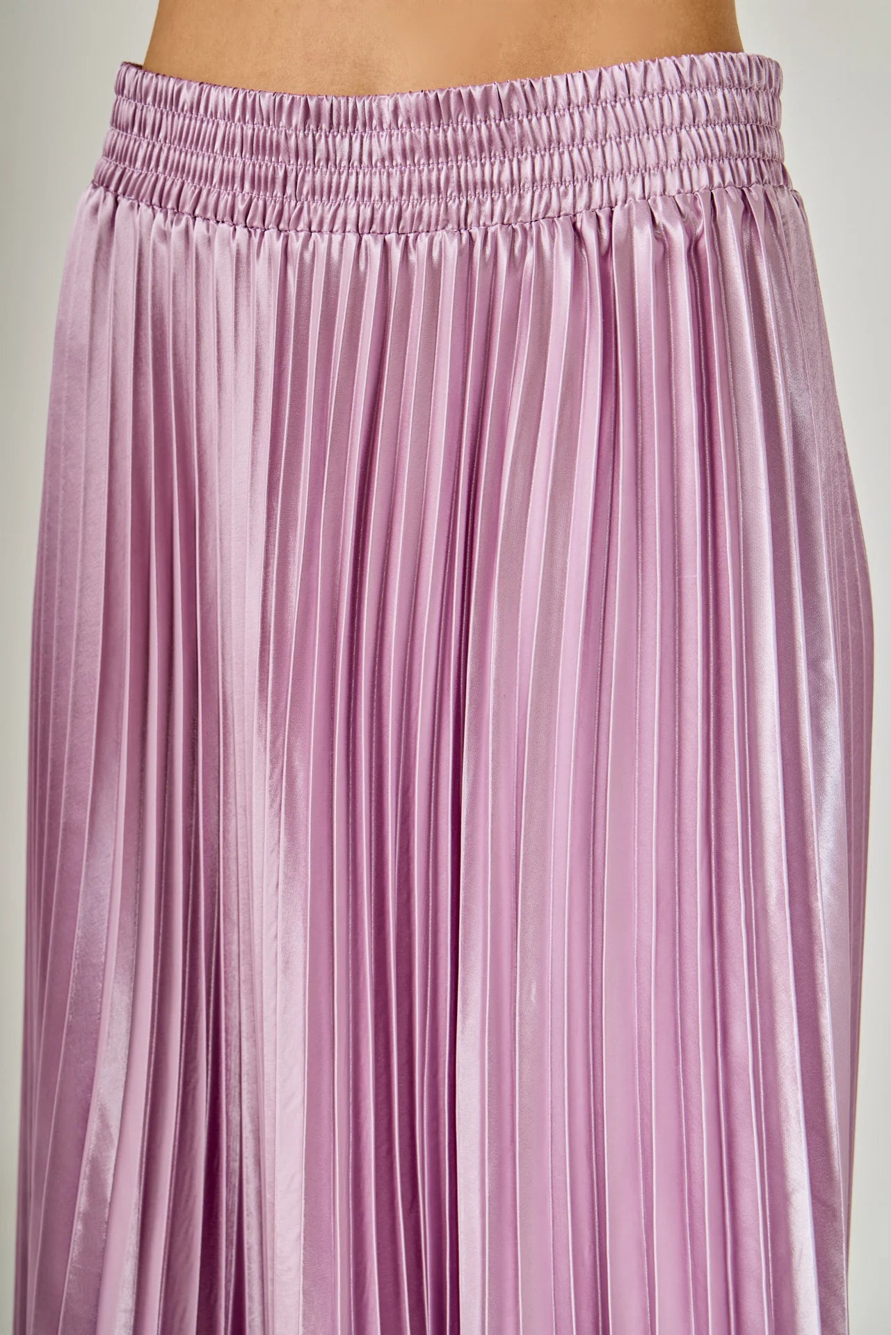 Close-up of a pink pleated skirt on a plain background