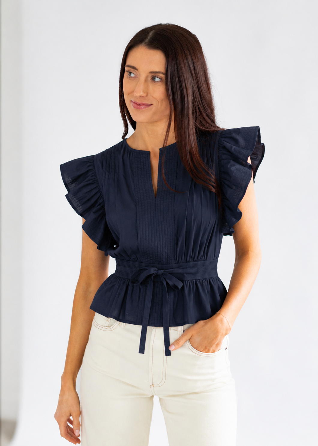 Woman wearing a navy blue blouse with ruffled sleeves on a white background
