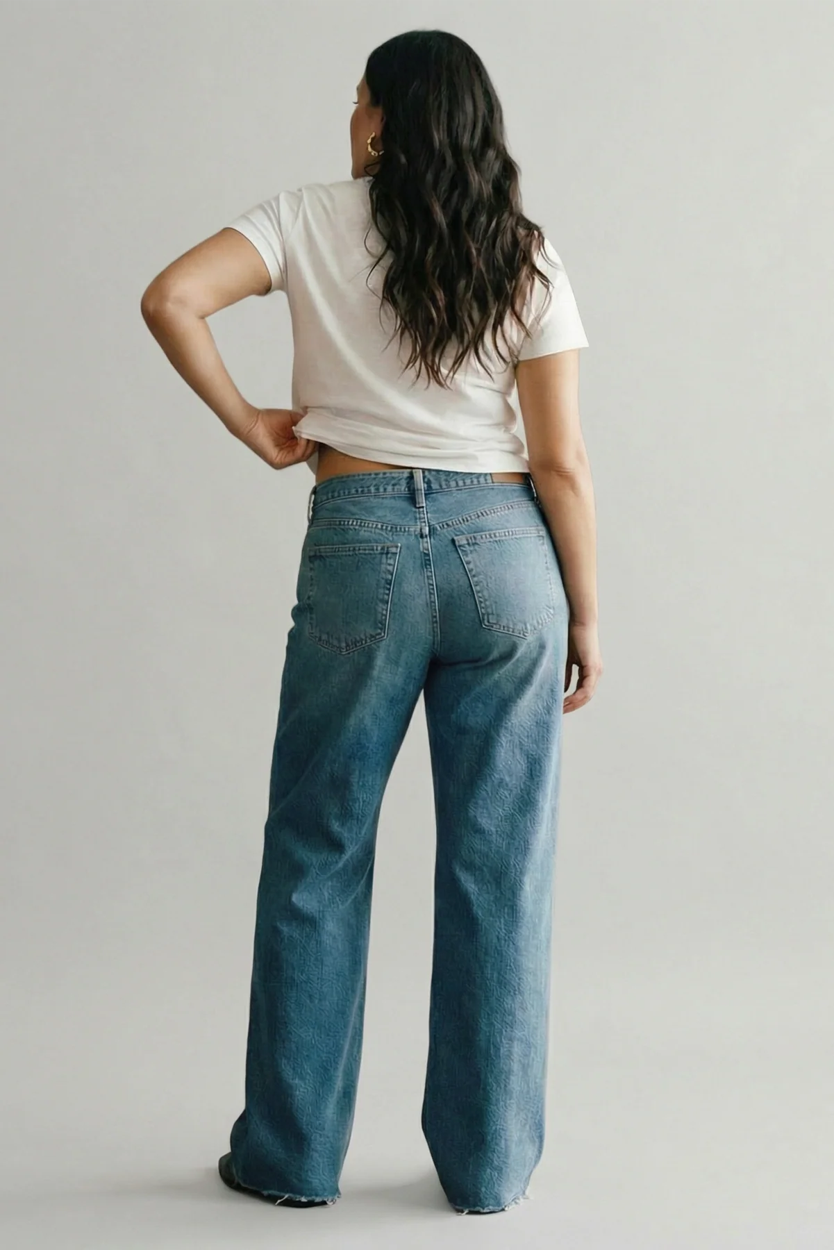 Person wearing blue jeans and a white t-shirt on a plain background