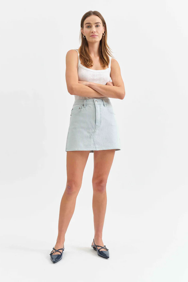 Woman wearing a light blue denim skirt on a white background