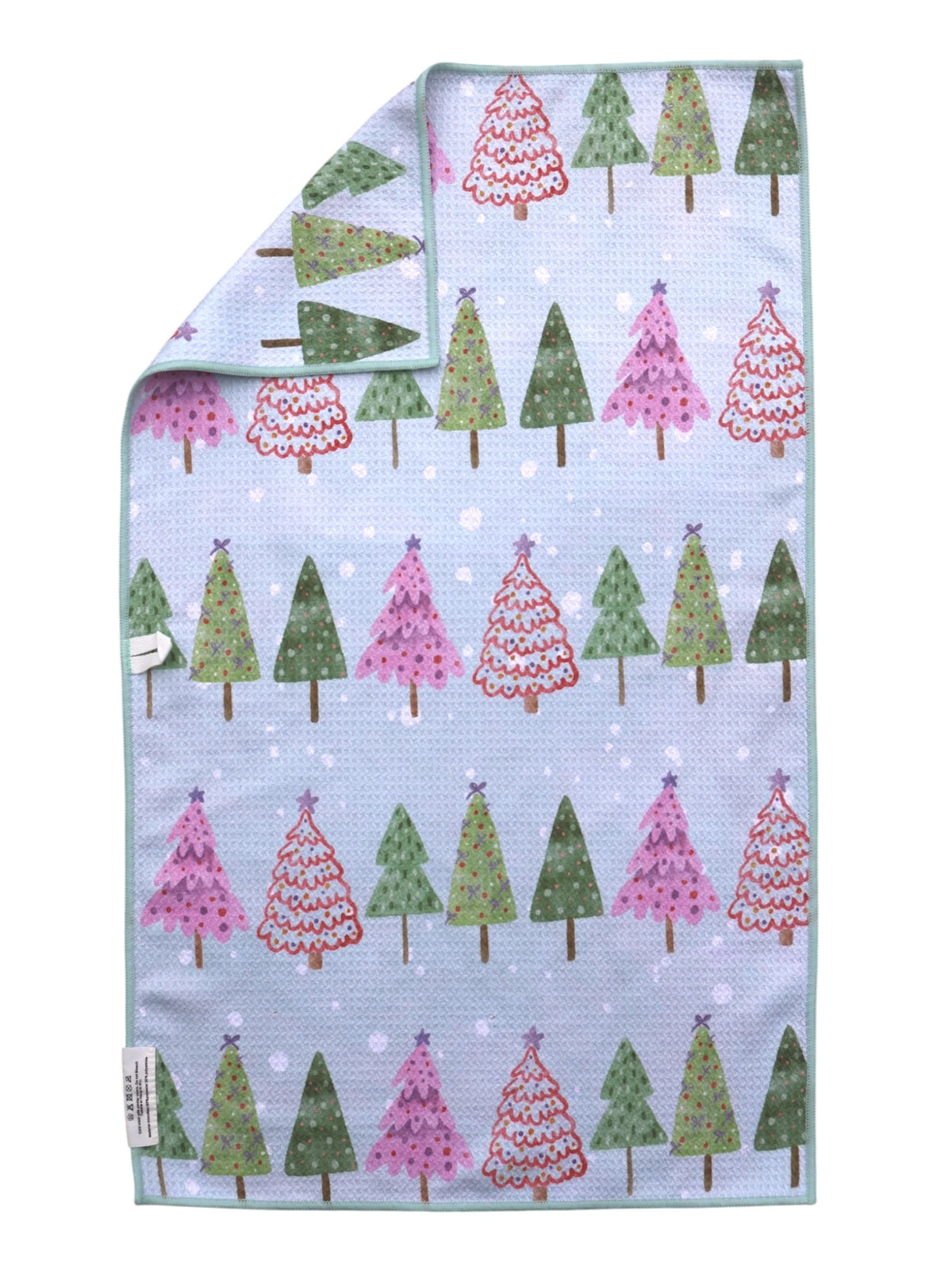 A double sided towel with a light blue background and a repeating pattern of Christmas trees in green and pink, shown with one corner folded over on a white background.