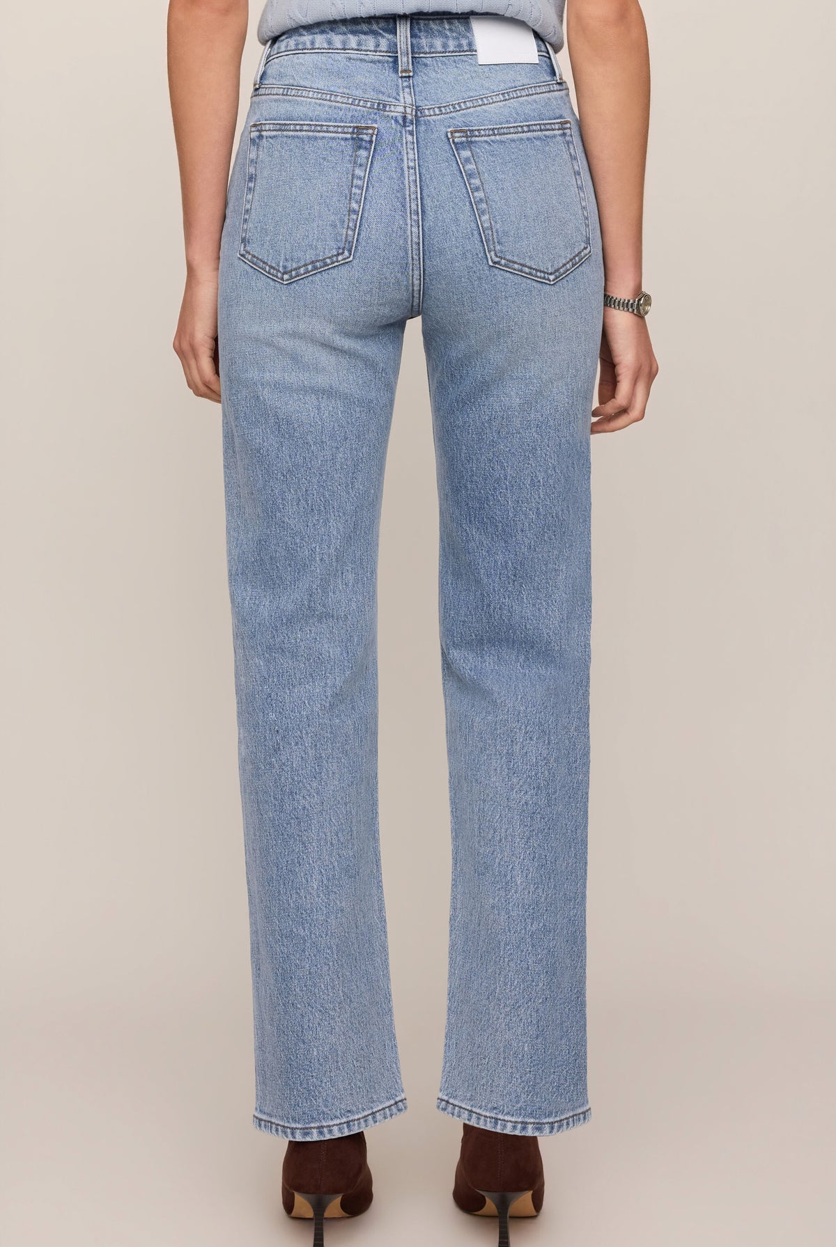 Light blue jeans worn by a person on a beige background