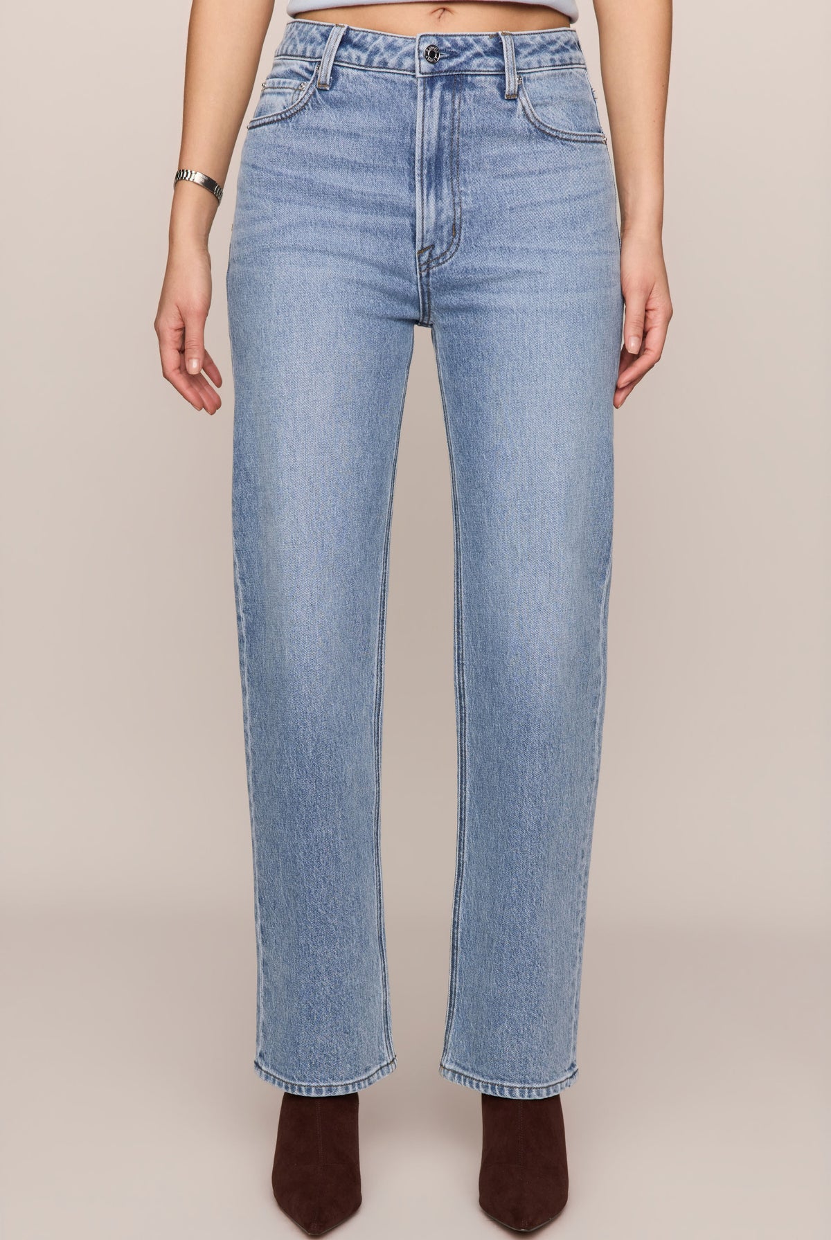Light blue jeans worn by a person on a beige background