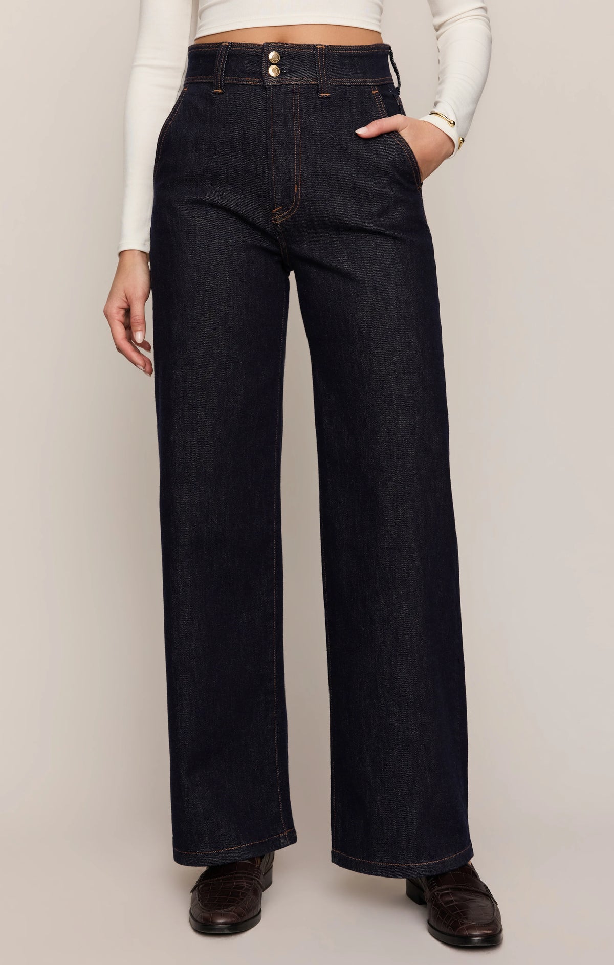 Person wearing dark blue wide-leg jeans on a plain background