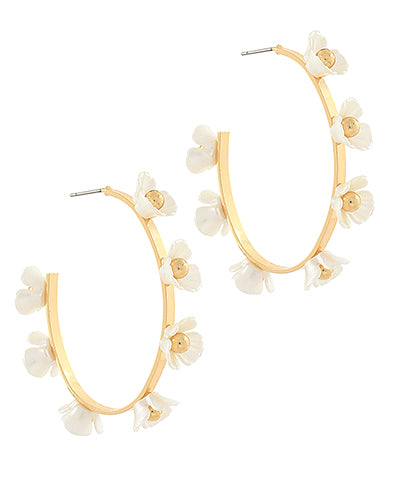 Gold hoop earrings with white floral attachments on a white background